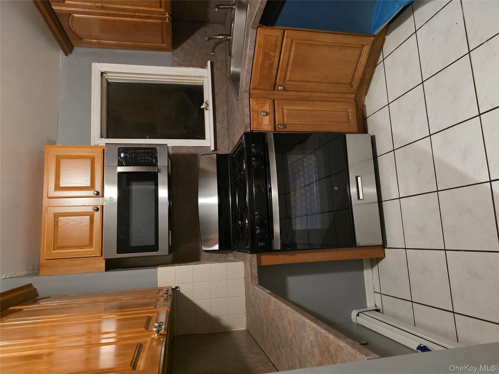 Kitchen with gas stove, backsplash, a baseboard radiator, dishwasher, and light tile patterned floors Kitchen with gas stove, backsplash, a baseboard radiator, dishwasher, and light tile patterned floors