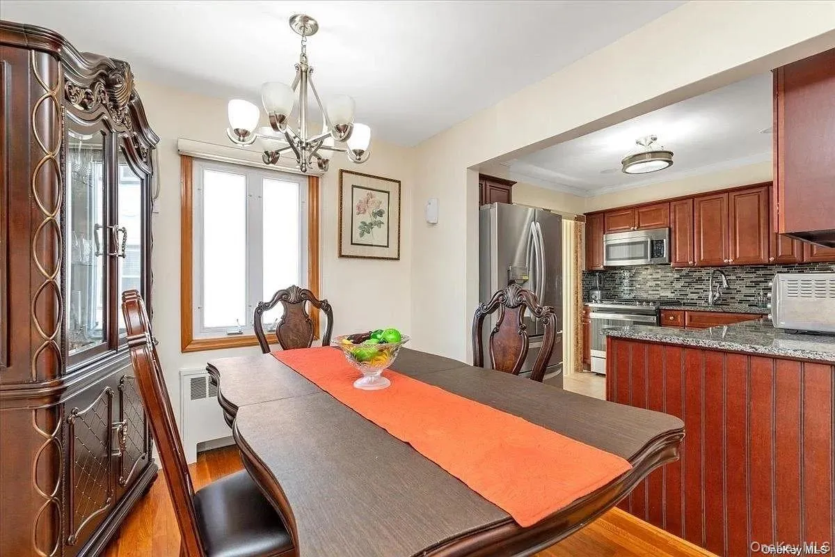 Dining area featuring light wood-type flooring, radiator, and a chandelier Dining area featuring light wood-type flooring, radiator, and a chandelier