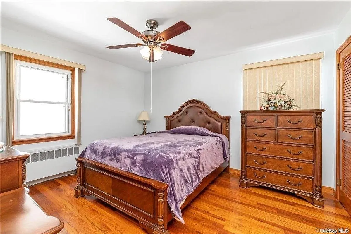 Bedroom featuring radiator, light wood-type flooring, and a ceiling fan Bedroom featuring radiator, light wood-type flooring, and a ceiling fan