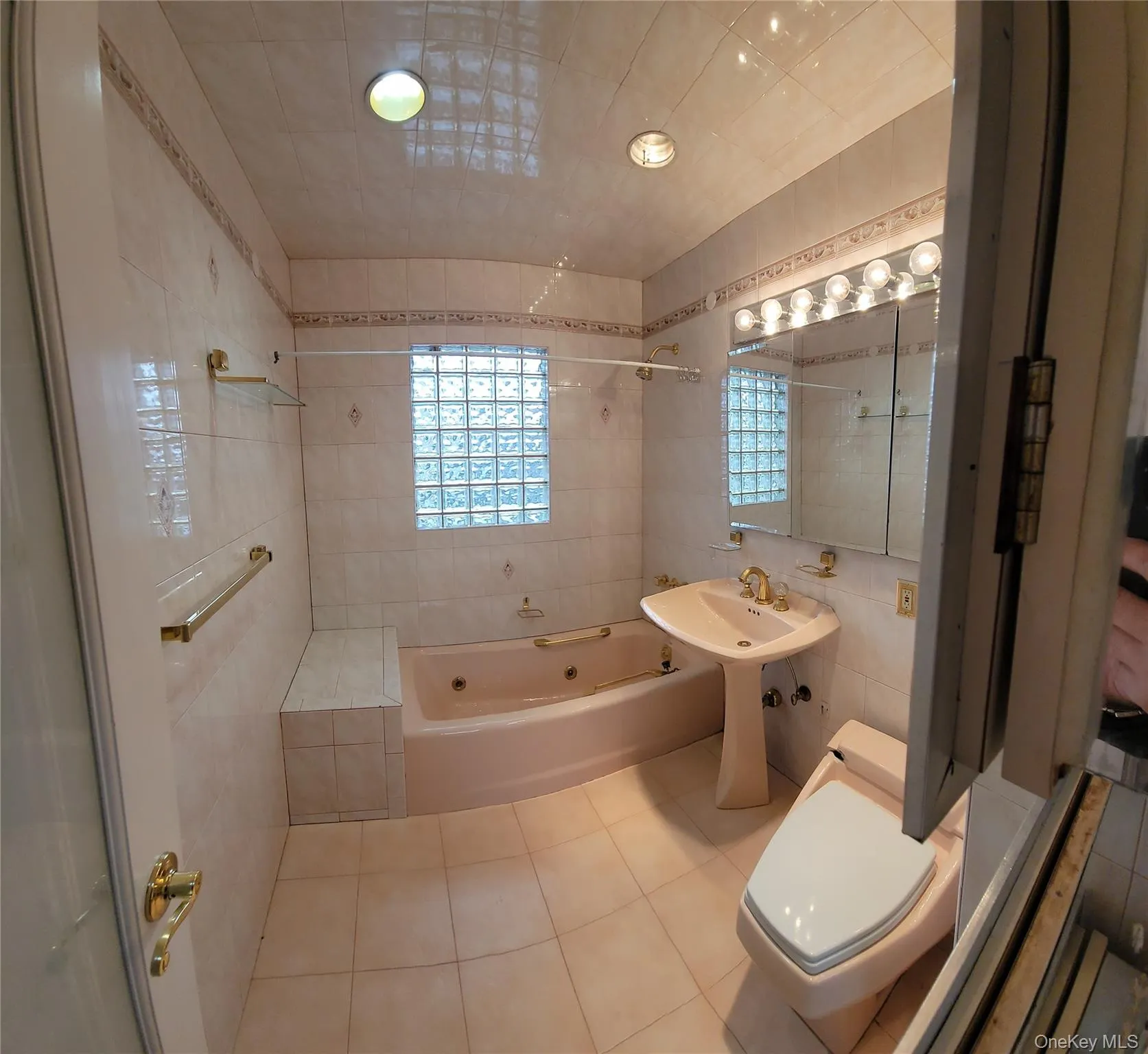 Full bathroom featuring tile patterned floors, tile walls, and a combined bath / shower with jetted tub Full bathroom featuring tile patterned floors, tile walls, and a combined bath / shower with jetted tub