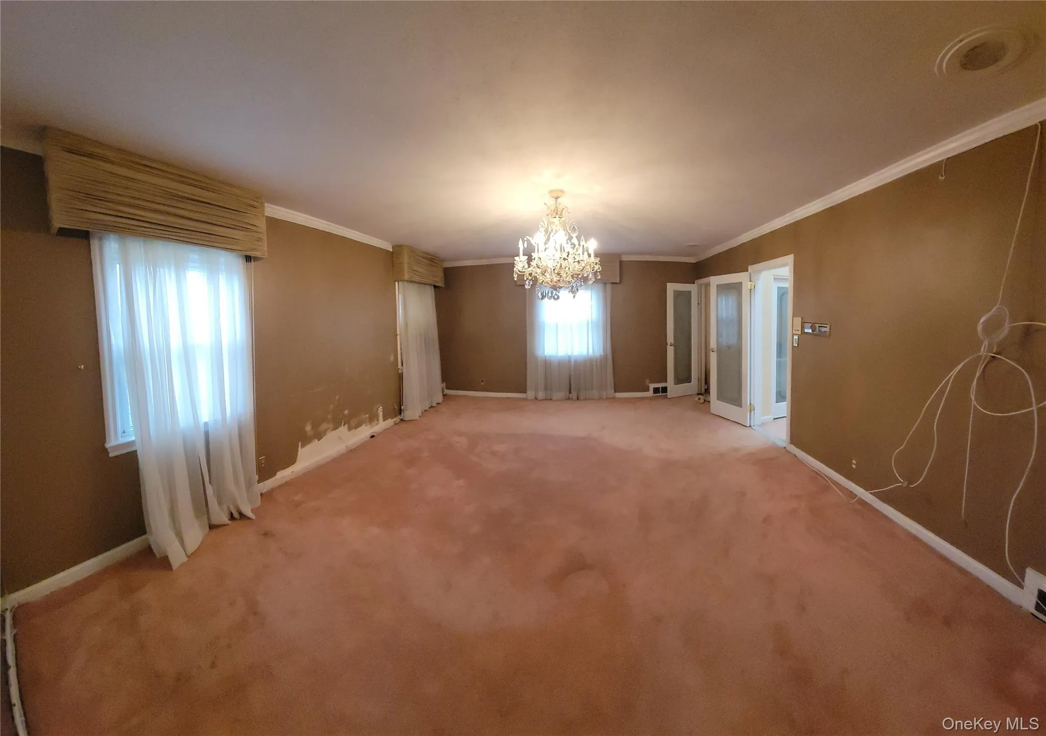 Unfurnished dining area featuring ornamental molding, a chandelier, and carpet flooring Unfurnished dining area featuring ornamental molding, a chandelier, and carpet flooring