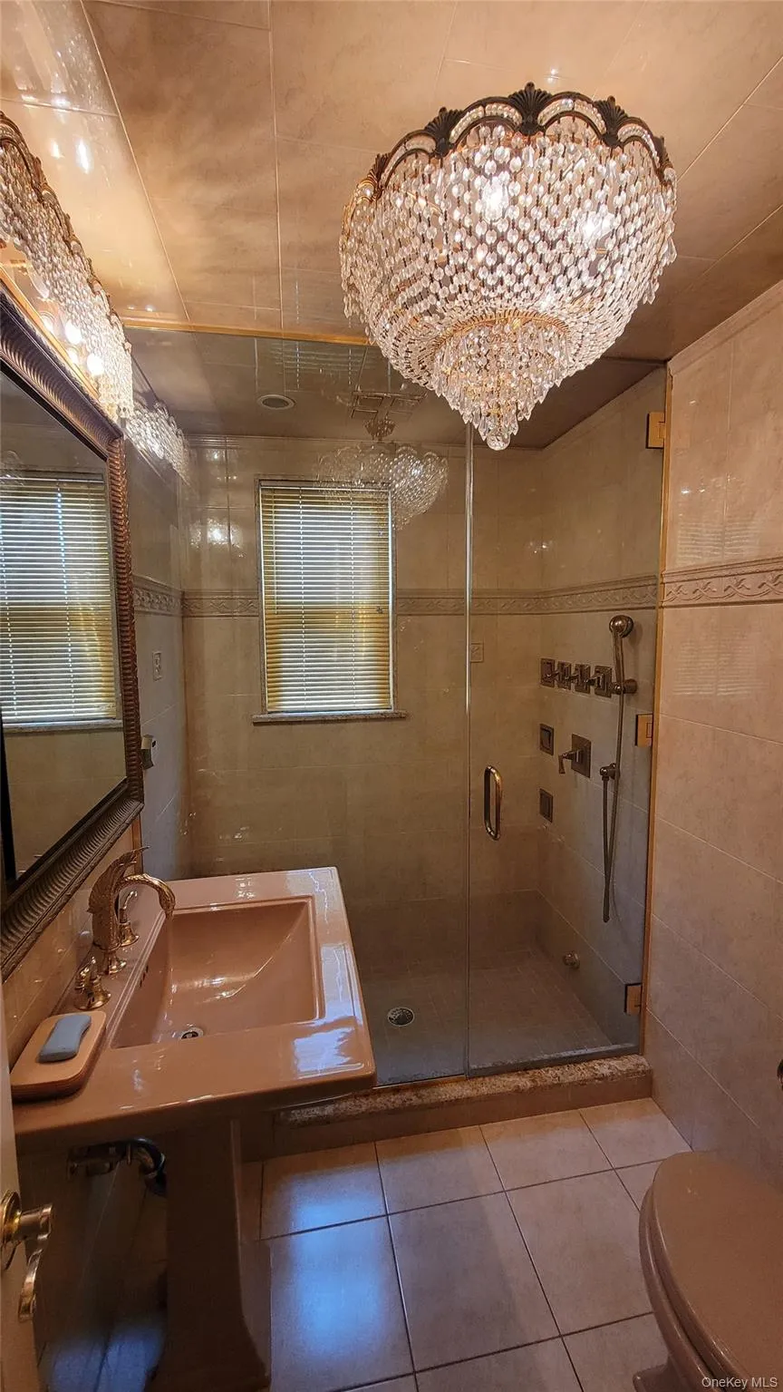 Bathroom with tile walls, tile patterned flooring, a shower stall, and a chandelier Bathroom with tile walls, tile patterned flooring, a shower stall, and a chandelier