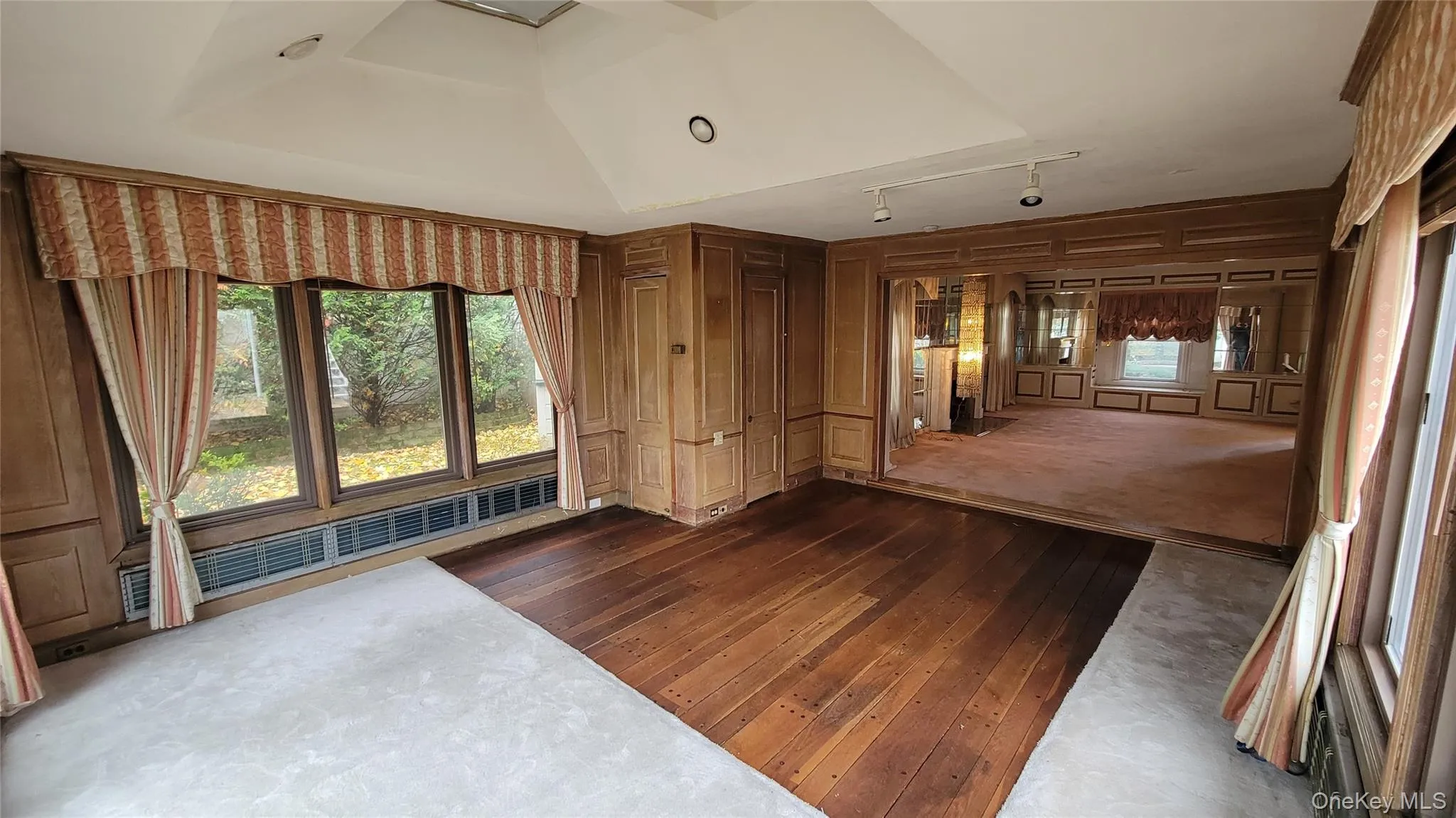 Spare room featuring healthy amount of natural light, dark wood finished floors, a decorative wall, and baseboard heating Spare room featuring healthy amount of natural light, dark wood finished floors, a decorative wall, and baseboard heating