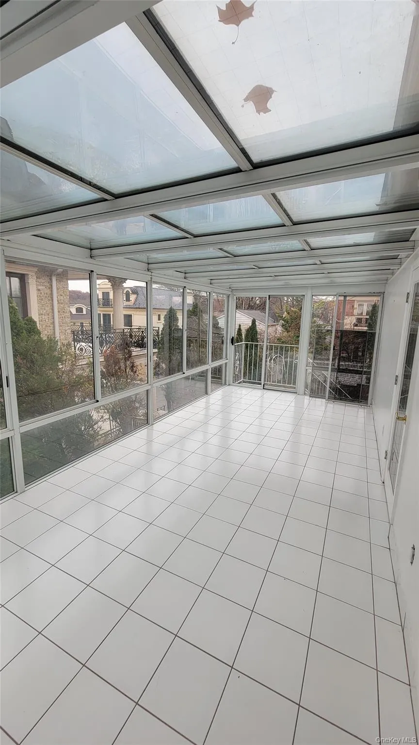 Unfurnished sunroom featuring tile patterned floors and floor to ceiling windows Unfurnished sunroom featuring tile patterned floors and floor to ceiling windows