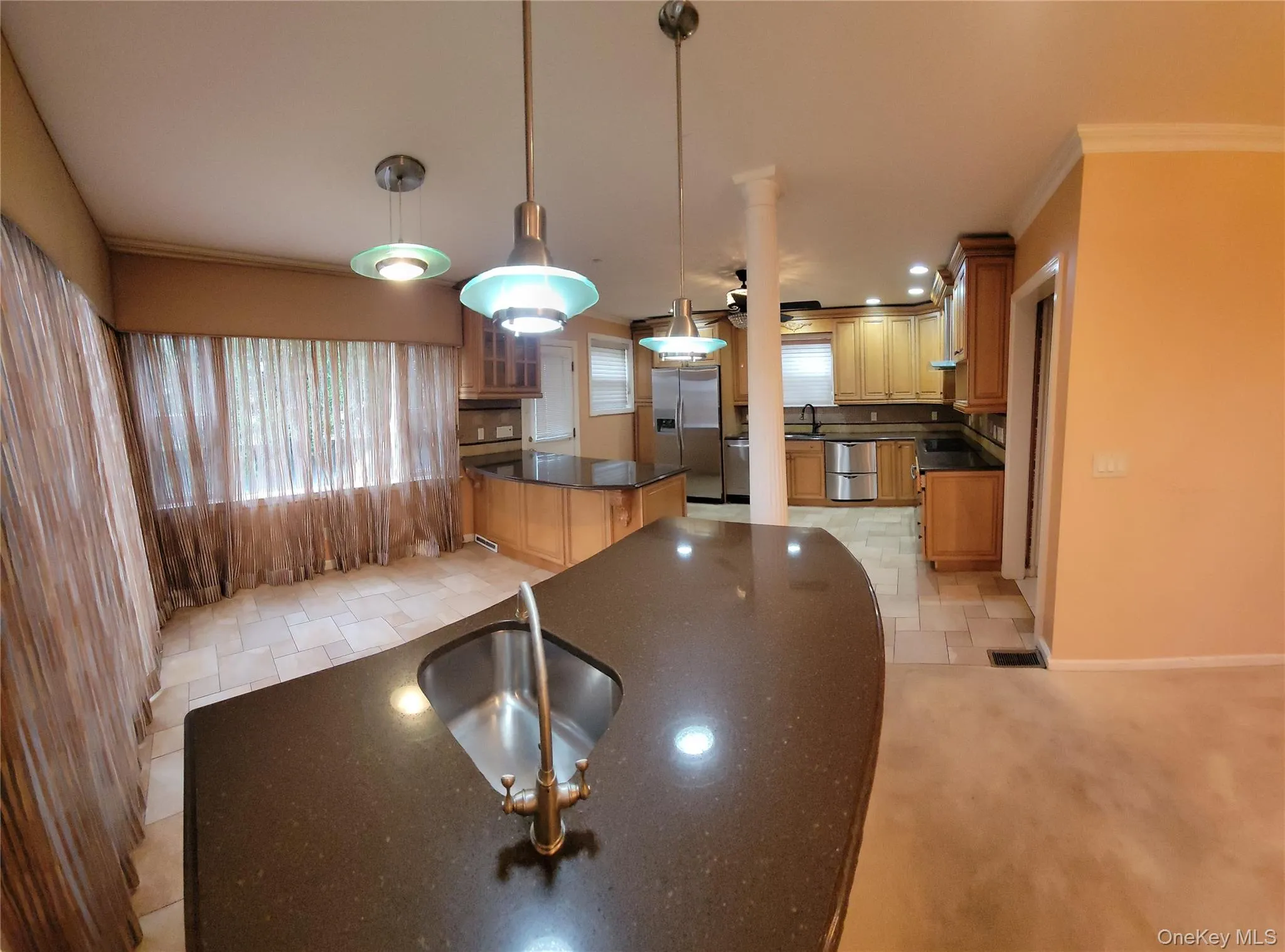 Kitchen with stainless steel appliances, ornamental molding, decorative light fixtures, a kitchen island, and dark stone counters Kitchen with stainless steel appliances, ornamental molding, decorative light fixtures, a kitchen island, and dark stone counters
