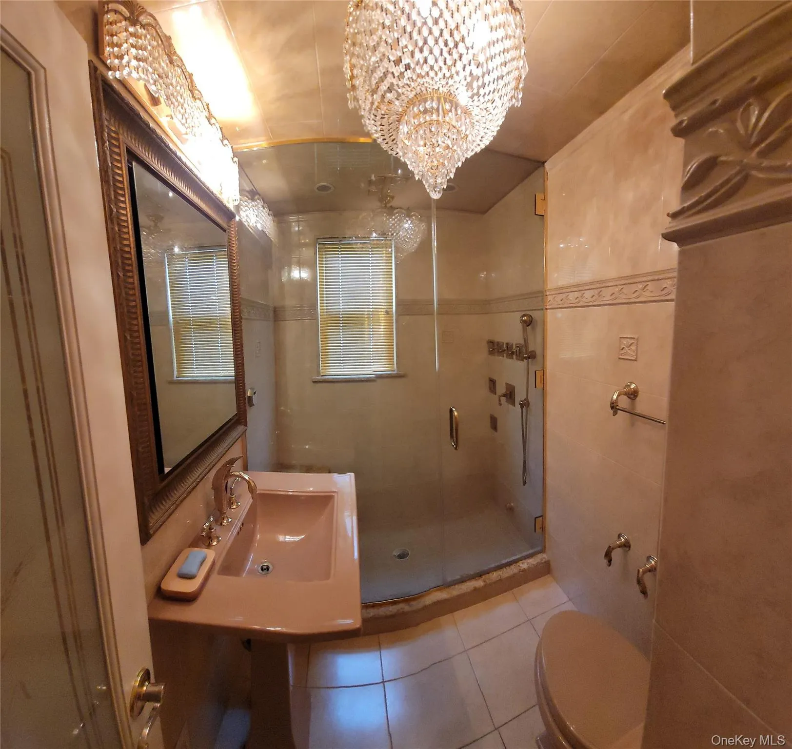 Bathroom with a stall shower, tile patterned flooring, a chandelier, and tile walls Bathroom with a stall shower, tile patterned flooring, a chandelier, and tile walls