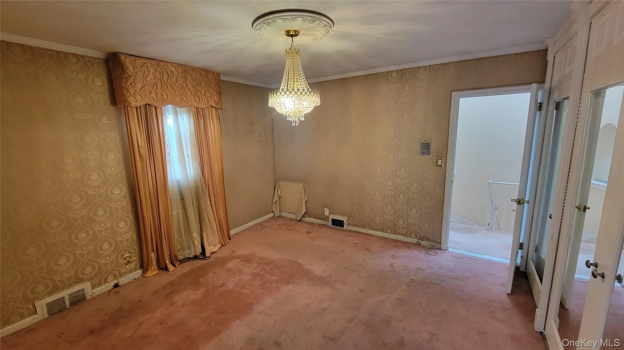 Unfurnished dining area with wallpapered walls, a chandelier, ornamental molding, and carpet floors Unfurnished dining area with wallpapered walls, a chandelier, ornamental molding, and carpet floors