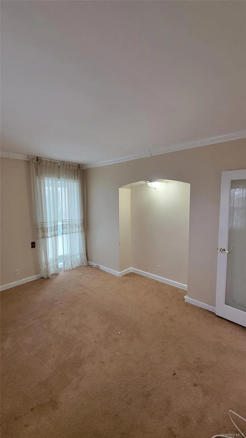 Carpeted empty room featuring crown molding and arched walkways Carpeted empty room featuring crown molding and arched walkways
