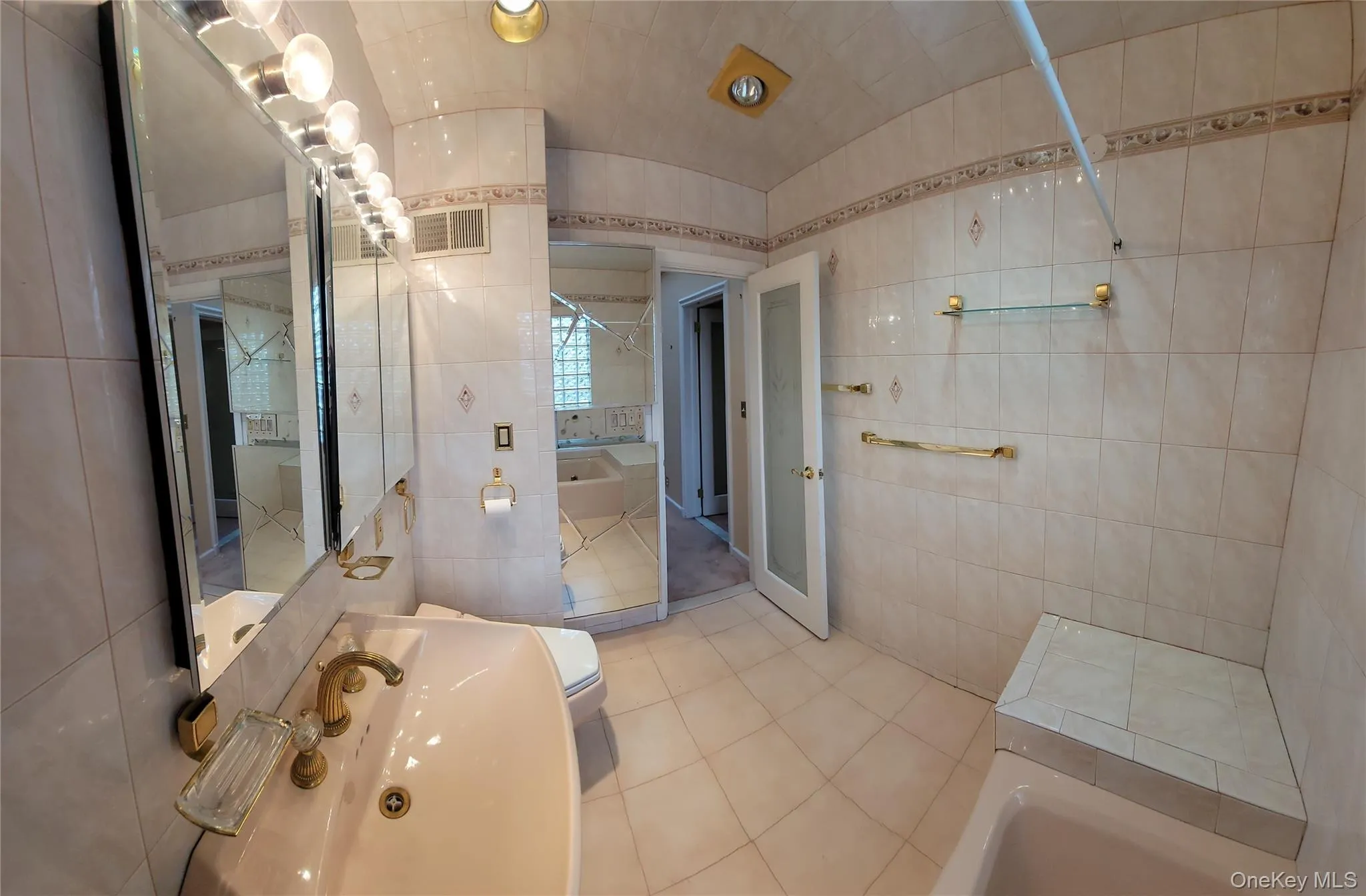 Full bathroom featuring tile walls, a tub to relax in, tile patterned flooring, and vaulted ceiling Full bathroom featuring tile walls, a tub to relax in, tile patterned flooring, and vaulted ceiling