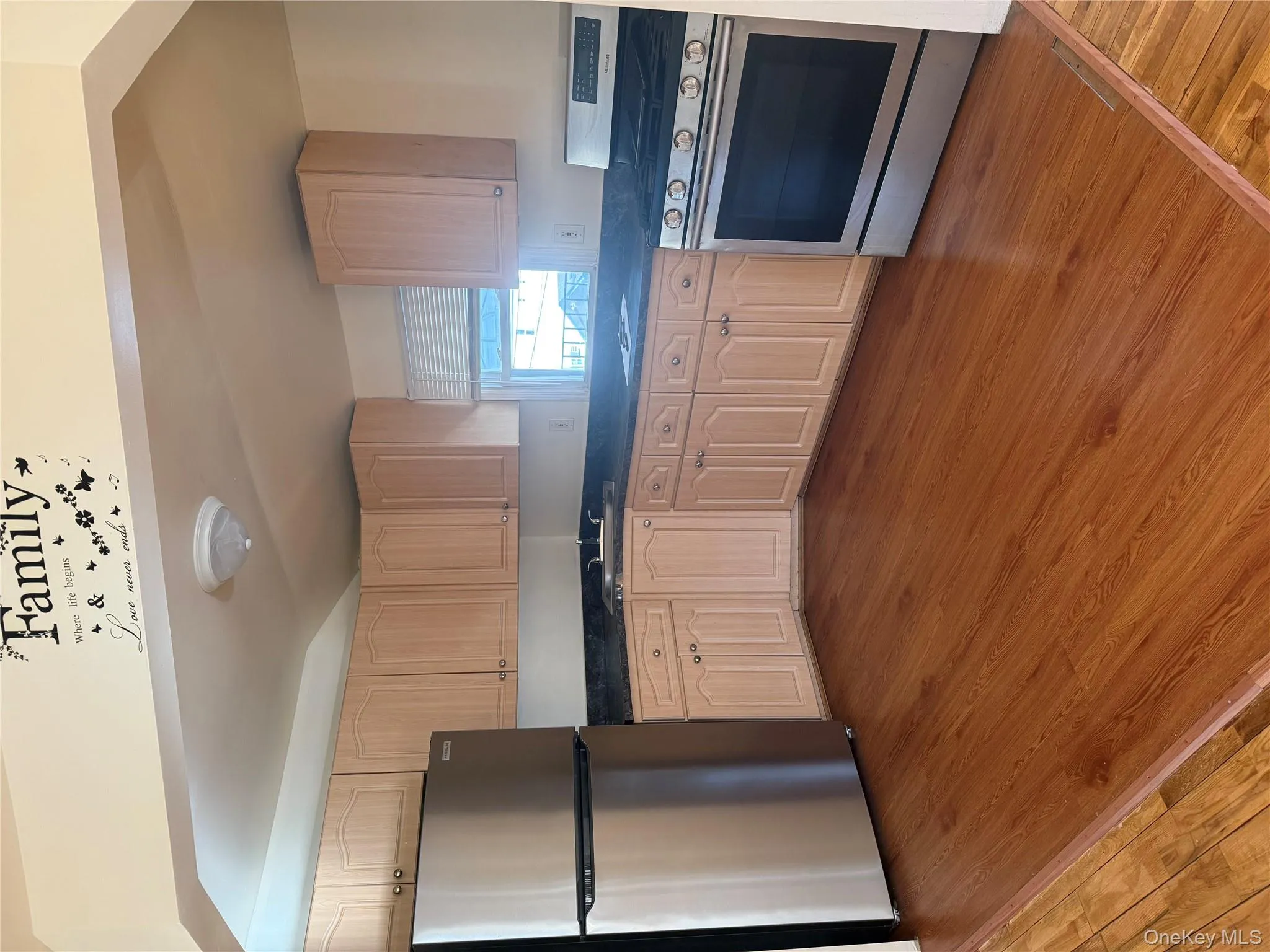 Kitchen featuring range, refrigerator, dark wood-type flooring, dark countertops, and light brown cabinets Kitchen featuring range, refrigerator, dark wood-type flooring, dark countertops, and light brown cabinets