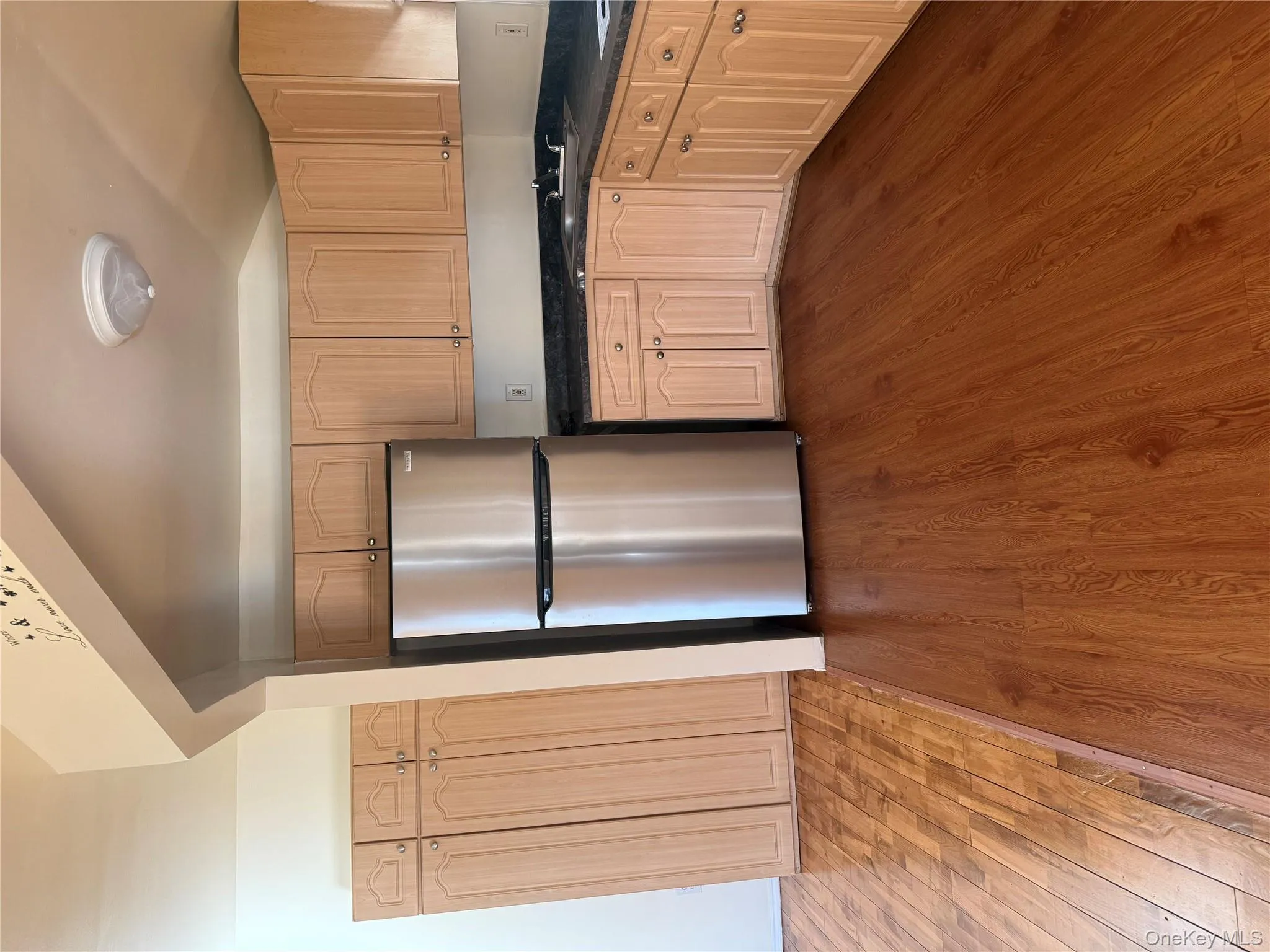 Kitchen with stainless steel fridge, dark wood-type flooring, and light brown cabinetry Kitchen with stainless steel fridge, dark wood-type flooring, and light brown cabinetry