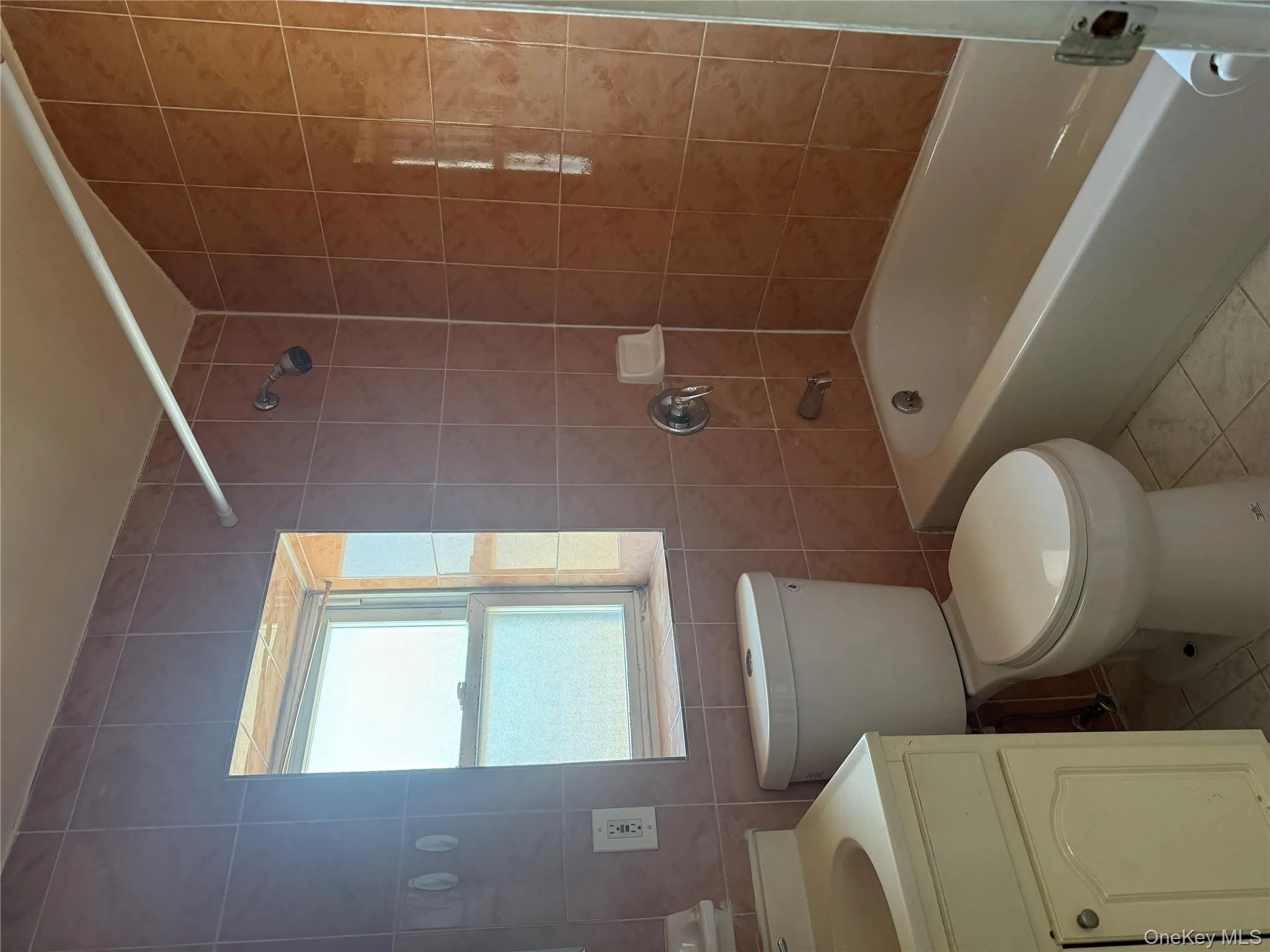 Full bathroom featuring tile walls, shower / tub combination, vanity, and light tile patterned floors Full bathroom featuring tile walls, shower / tub combination, vanity, and light tile patterned floors