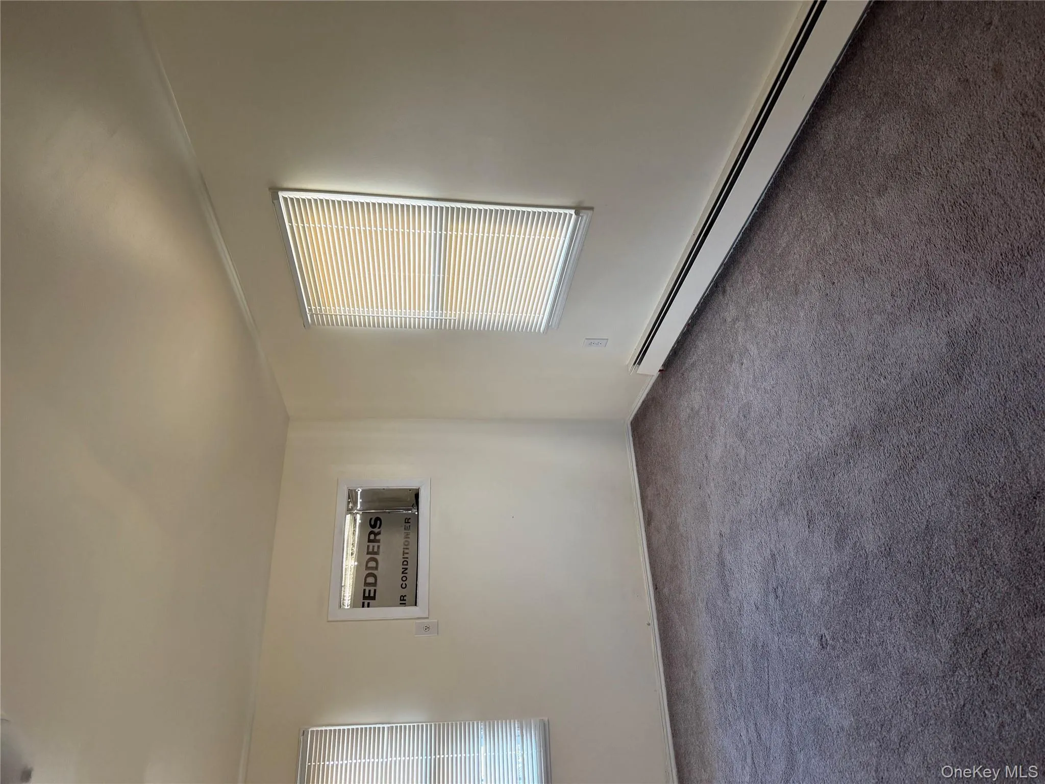 Carpeted spare room with baseboard heating and a wall unit AC Carpeted spare room with baseboard heating and a wall unit AC