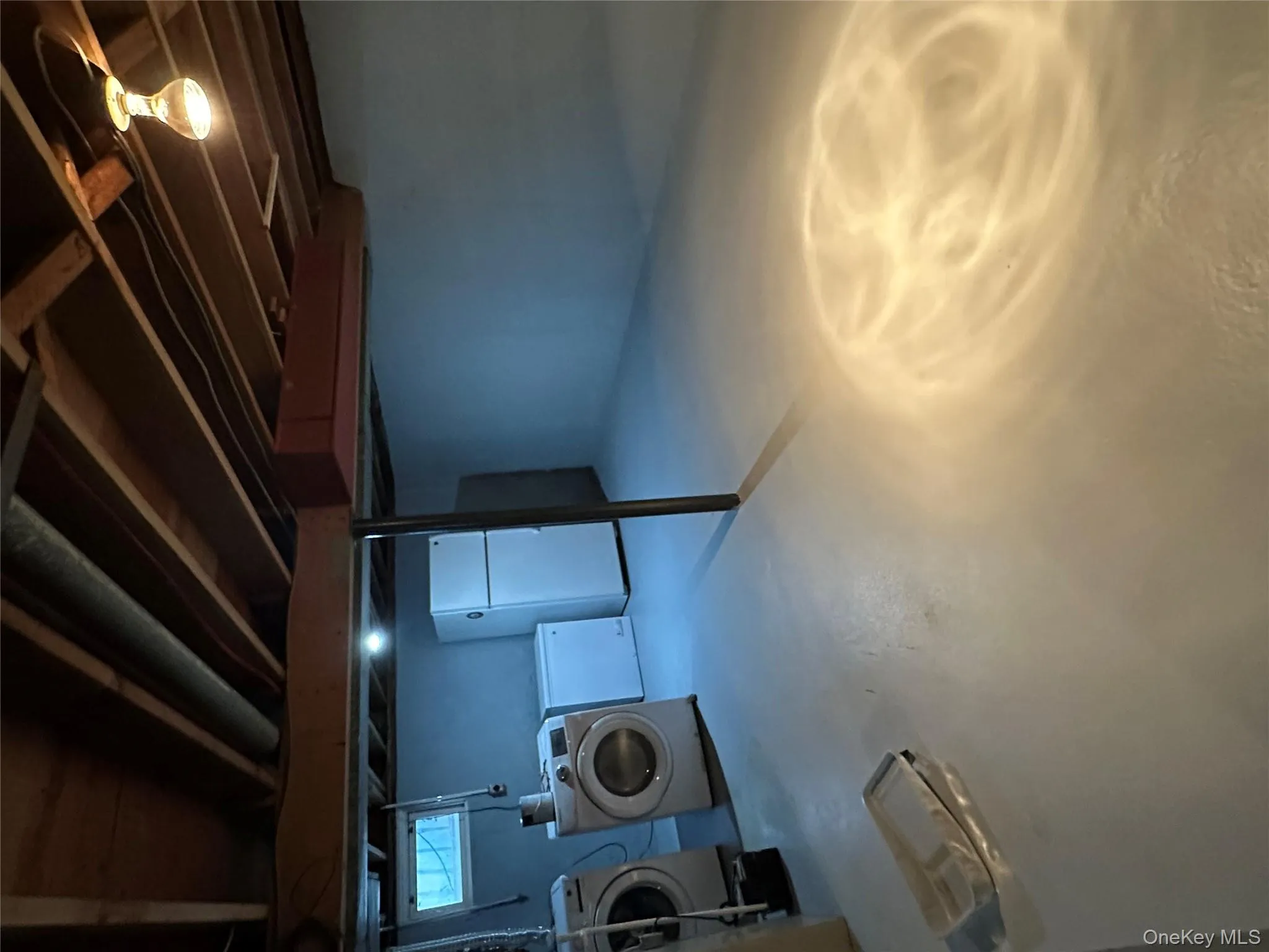 Unfinished below grade area featuring refrigerator and independent washer and dryer Unfinished below grade area featuring refrigerator and independent washer and dryer