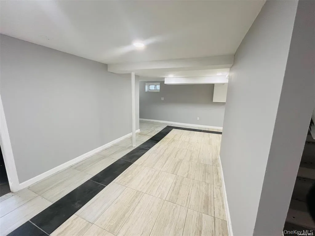 Basement with baseboards and light tile patterned flooring Basement with baseboards and light tile patterned flooring