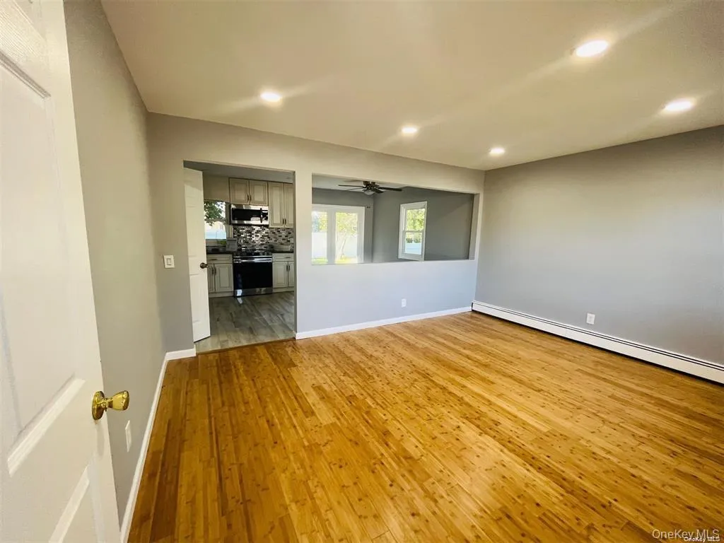 Empty room with light wood-style flooring, a baseboard radiator, recessed lighting, and a ceiling fan Empty room with light wood-style flooring, a baseboard radiator, recessed lighting, and a ceiling fan
