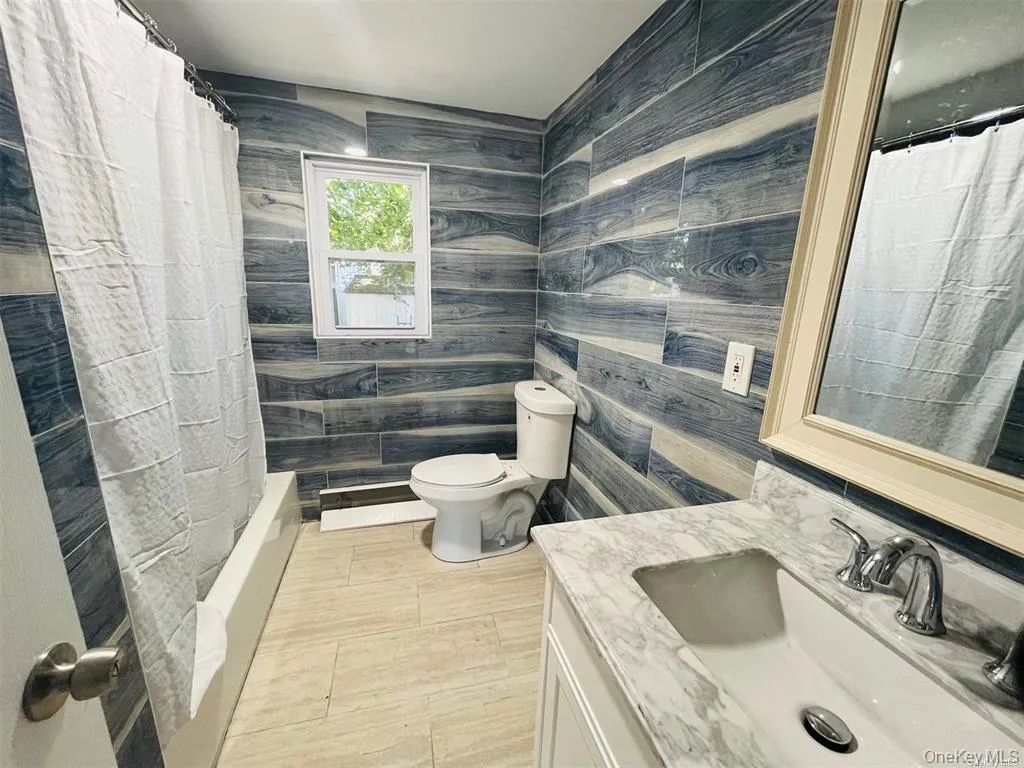 Full bath featuring vanity and tile walls Full bath featuring vanity and tile walls