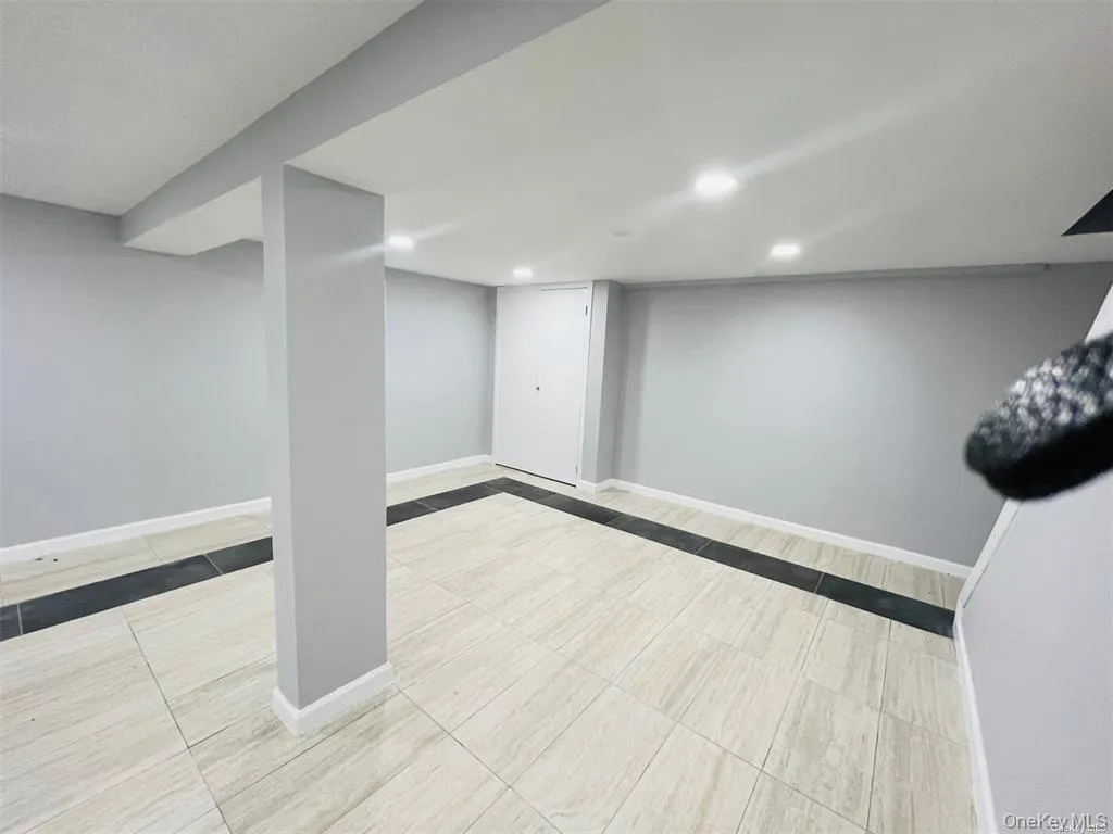 Finished basement with light tile patterned flooring and recessed lighting Finished basement with light tile patterned flooring and recessed lighting