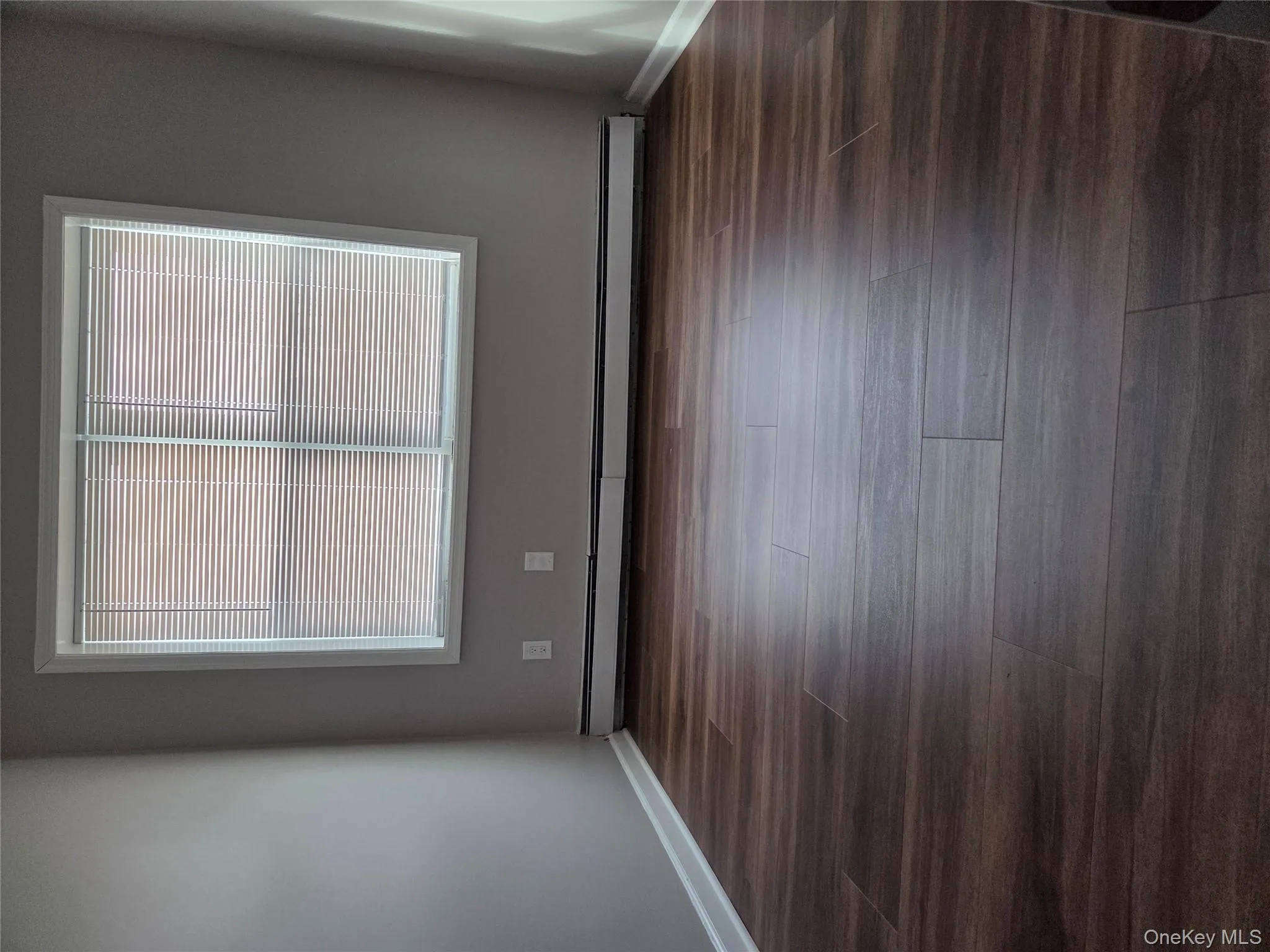 Empty room with a baseboard radiator and dark wood-style flooring Empty room with a baseboard radiator and dark wood-style flooring