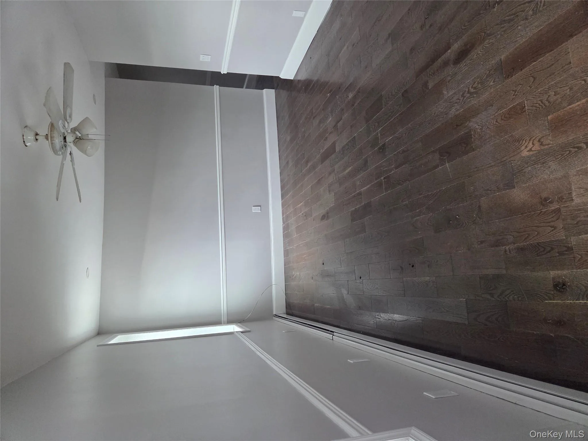 Spare room featuring a baseboard radiator, dark wood-style flooring, and a ceiling fan Spare room featuring a baseboard radiator, dark wood-style flooring, and a ceiling fan