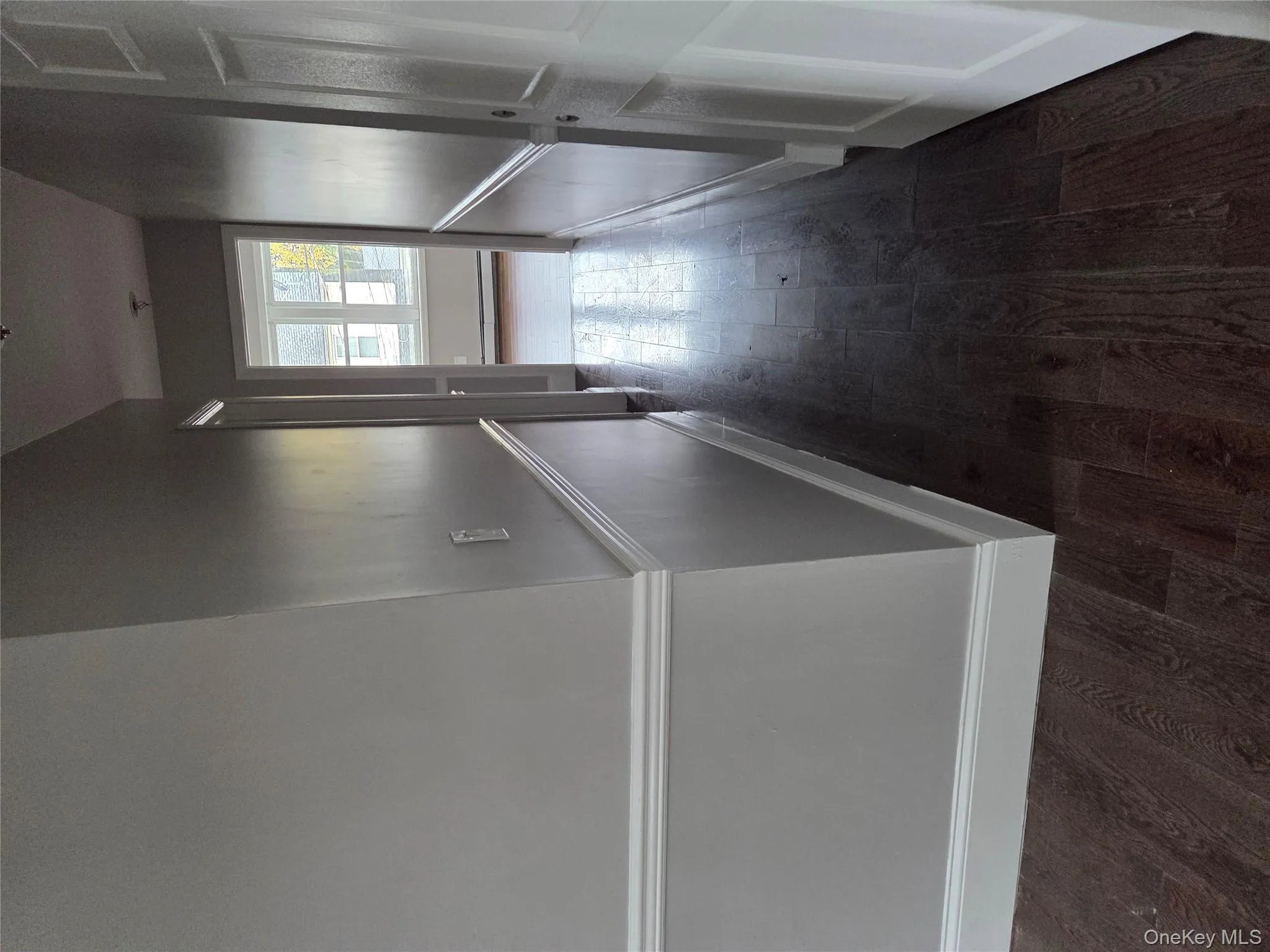 Corridor with dark wood-type flooring, a wainscoted wall, and a baseboard radiator Corridor with dark wood-type flooring, a wainscoted wall, and a baseboard radiator
