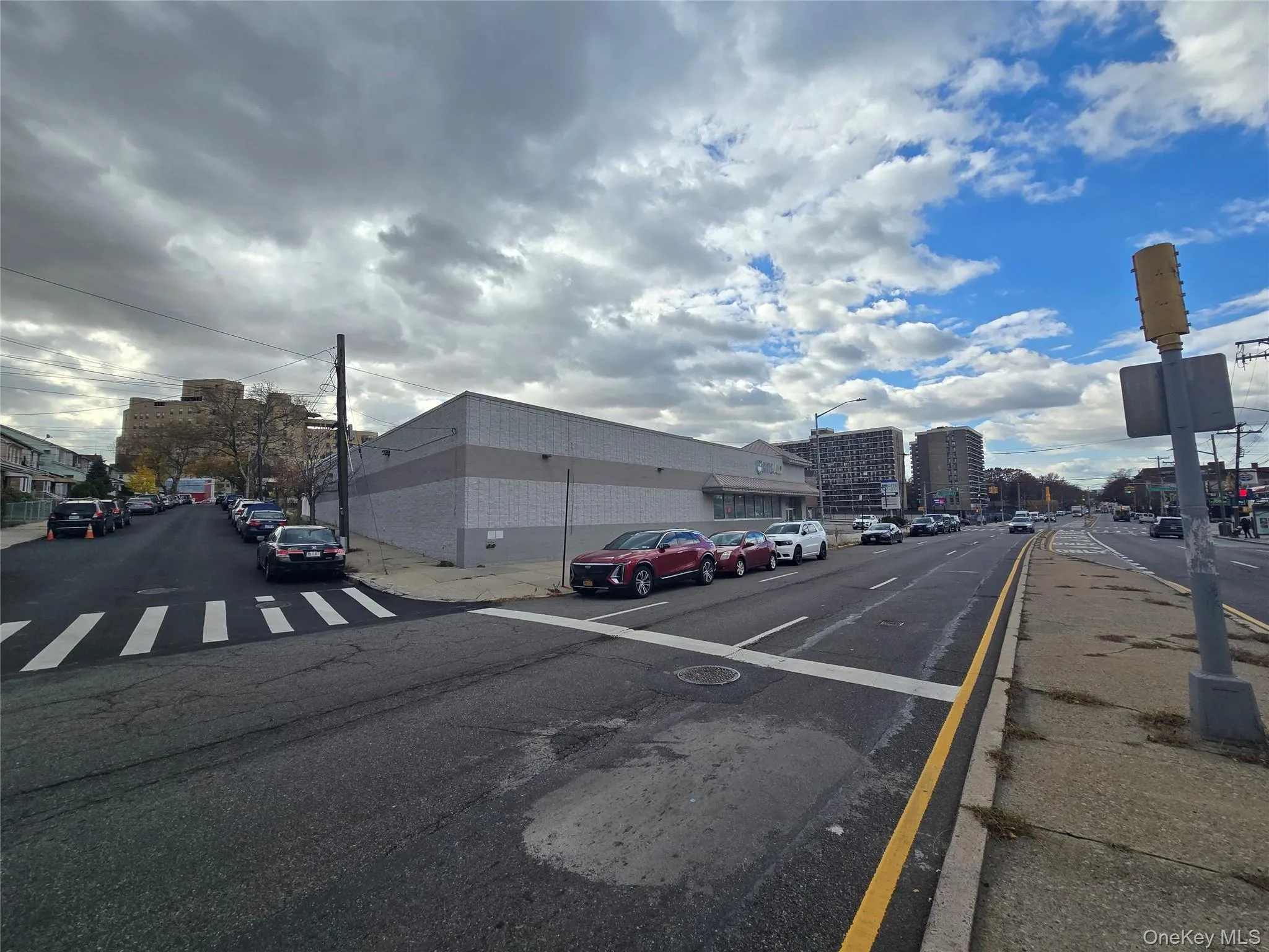 View of asphalt street with sidewalks, curbs, street lights, and a city view View of asphalt street with sidewalks, curbs, street lights, and a city view