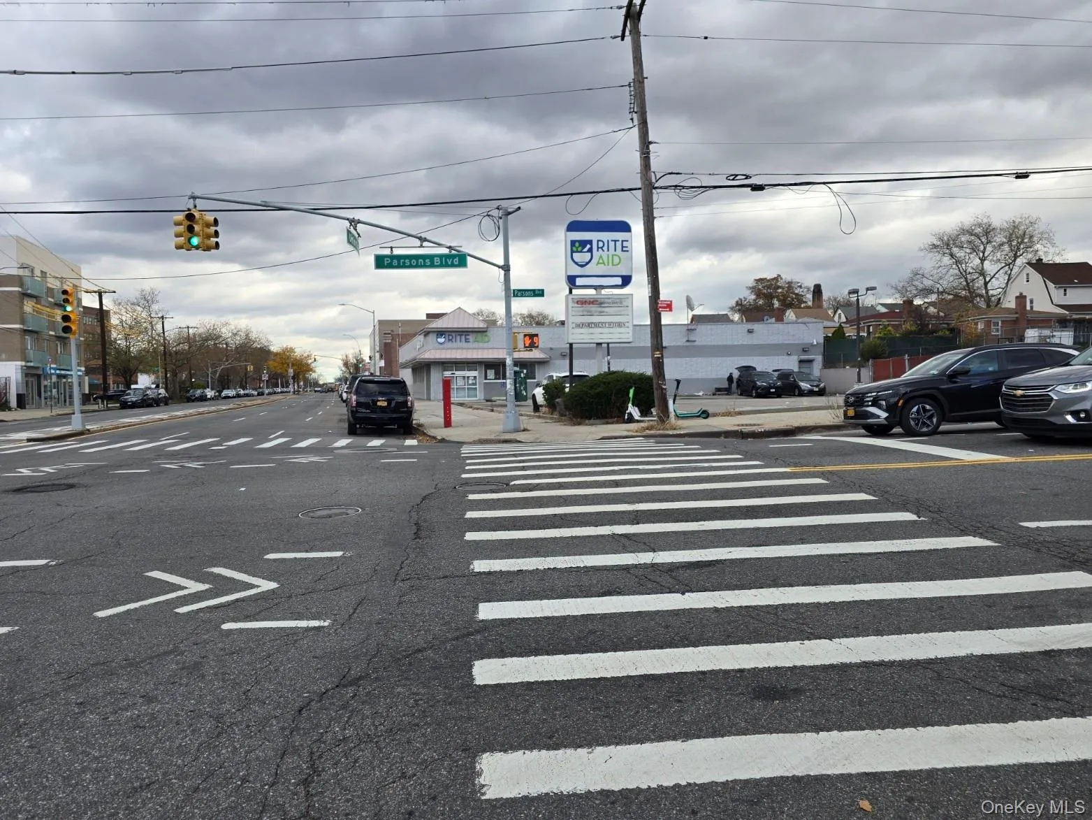 View of asphalt street featuring traffic lights, curbs, sidewalks, and street lighting View of asphalt street featuring traffic lights, curbs, sidewalks, and street lighting