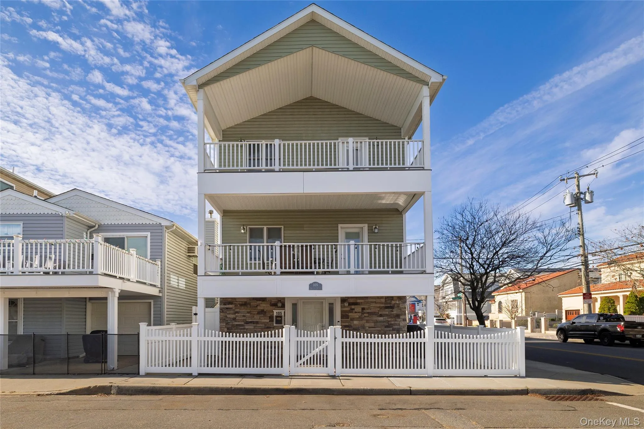 View of front of property featuring a fenced front yard, stone siding, and a balcony View of front of property featuring a fenced front yard, stone siding, and a balcony