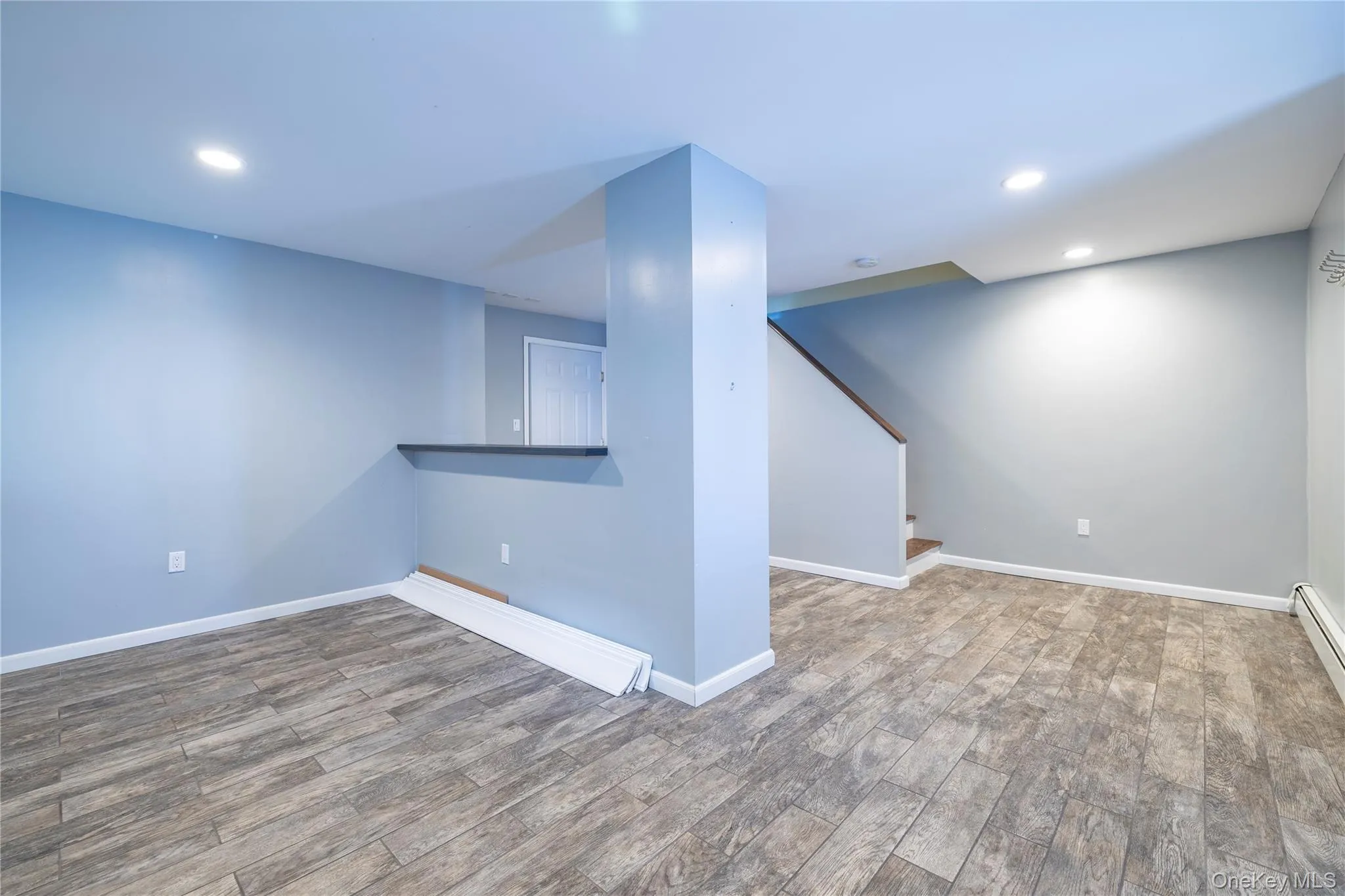 Spare room featuring recessed lighting, wood finished floors, and stairs Spare room featuring recessed lighting, wood finished floors, and stairs