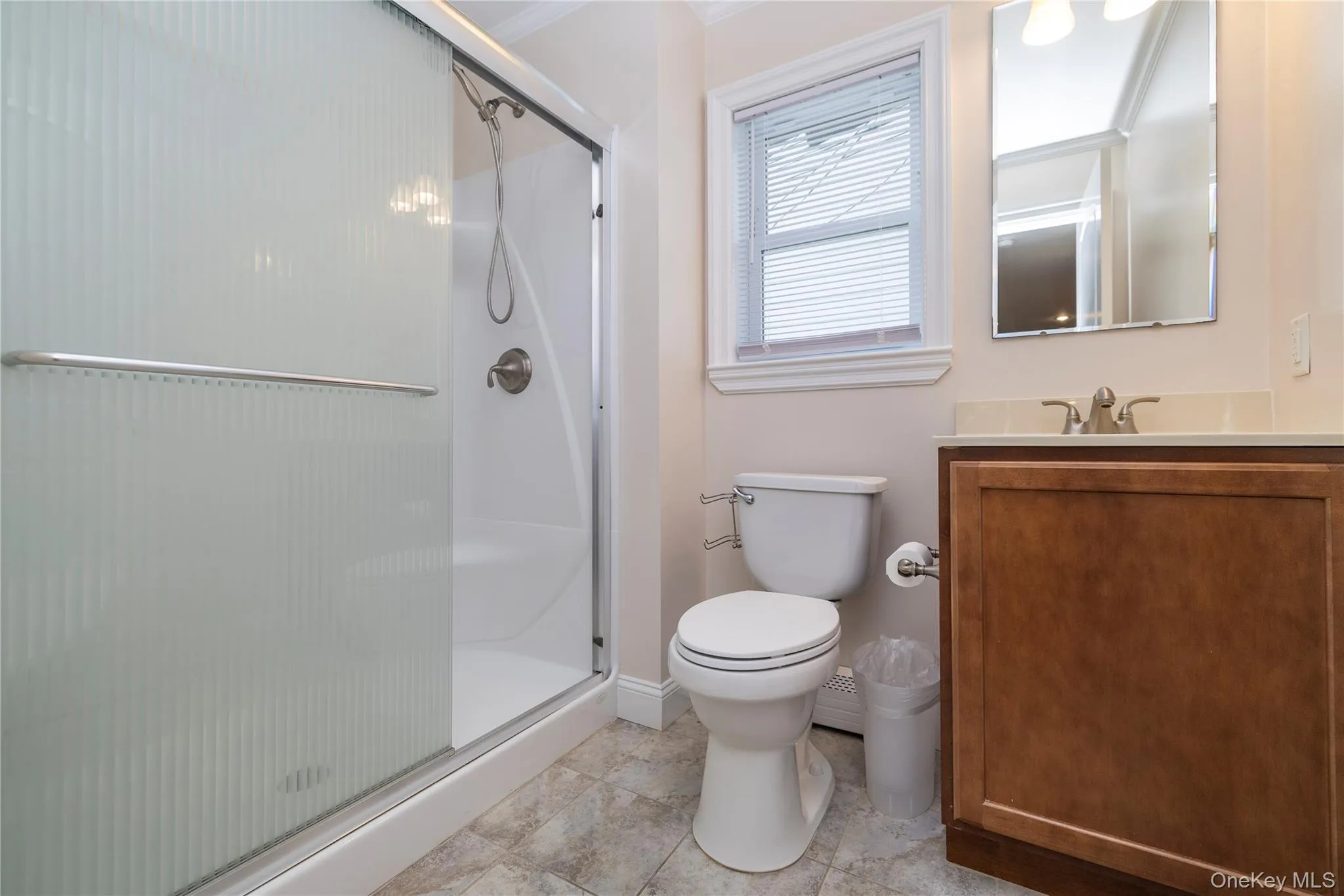 Full bath featuring a shower stall, vanity, crown molding, and light tile patterned flooring Full bath featuring a shower stall, vanity, crown molding, and light tile patterned flooring