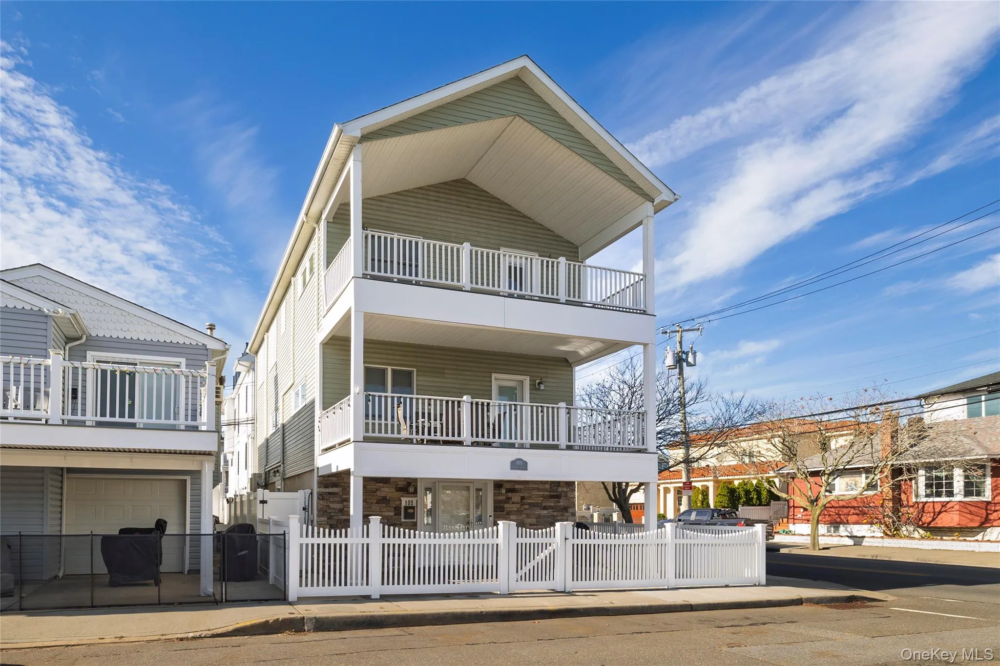 View of front of home with stone siding, a fenced front yard, and a balcony View of front of home with stone siding, a fenced front yard, and a balcony