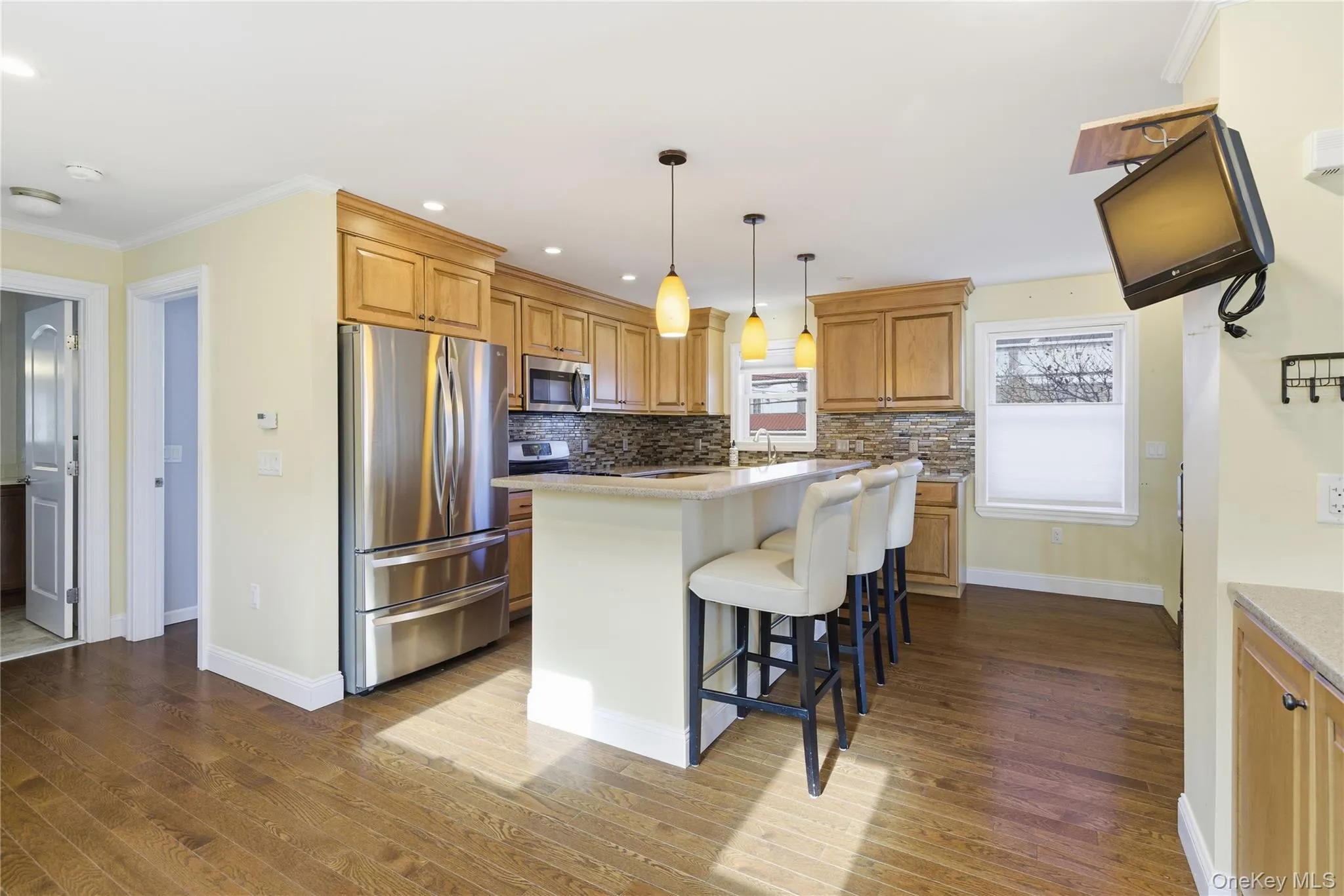 Kitchen with a breakfast bar, appliances with stainless steel finishes, decorative backsplash, decorative light fixtures, and a kitchen island Kitchen with a breakfast bar, appliances with stainless steel finishes, decorative backsplash, decorative light fixtures, and a kitchen island