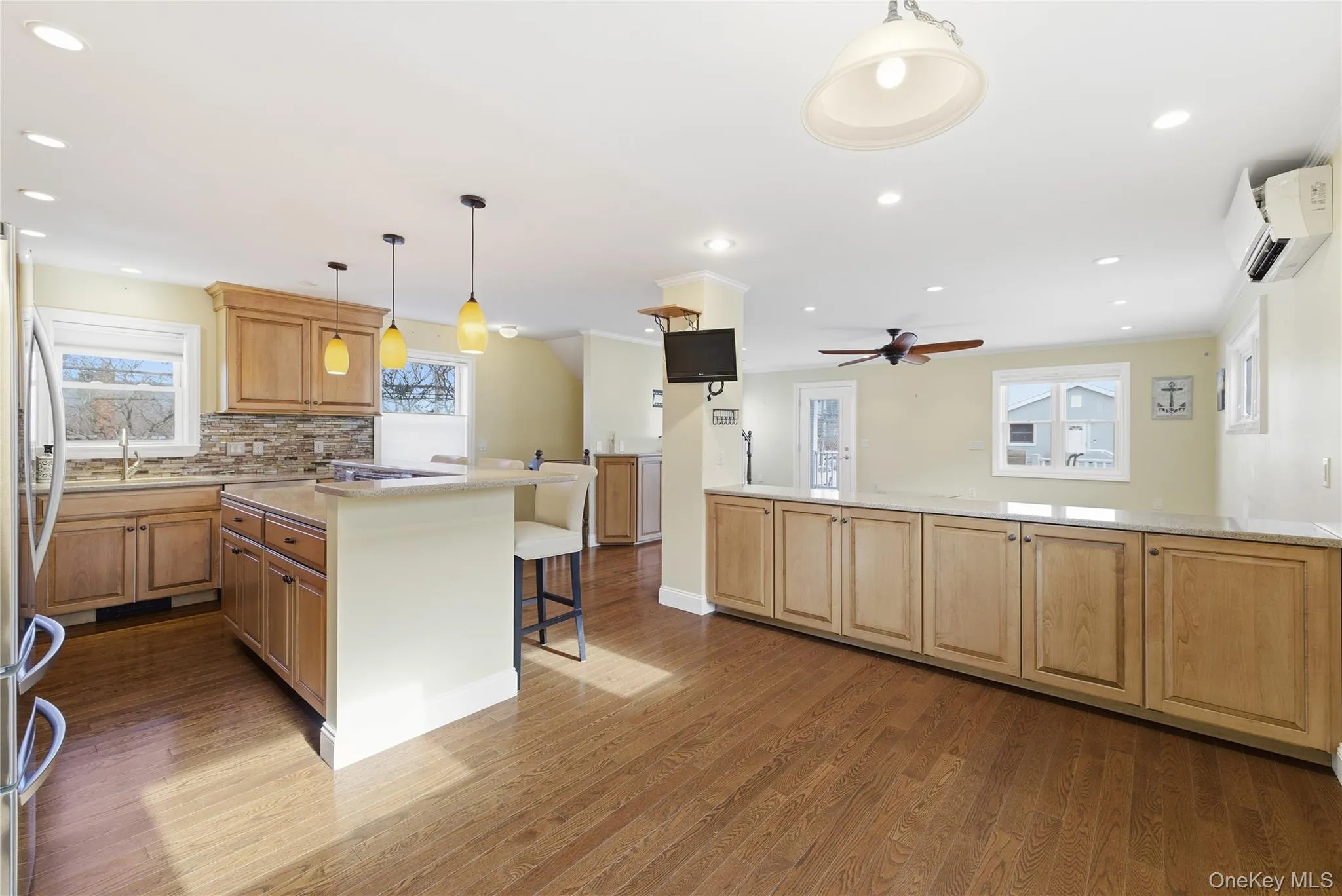 Kitchen featuring a kitchen breakfast bar, decorative light fixtures, dark wood-type flooring, light stone counters, and freestanding refrigerator Kitchen featuring a kitchen breakfast bar, decorative light fixtures, dark wood-type flooring, light stone counters, and freestanding refrigerator