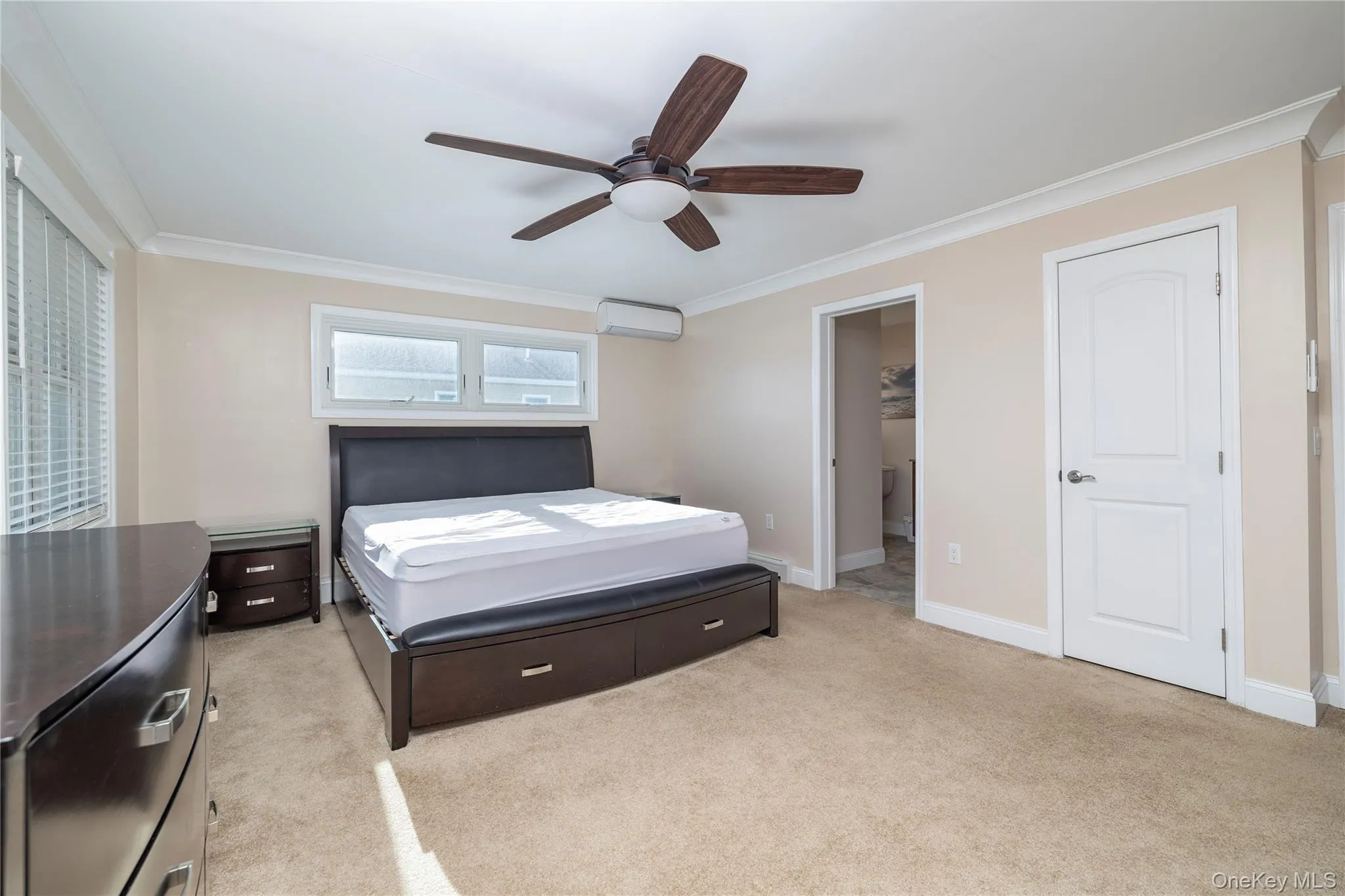 Bedroom with crown molding, light colored carpet, ceiling fan, and an AC wall unit Bedroom with crown molding, light colored carpet, ceiling fan, and an AC wall unit