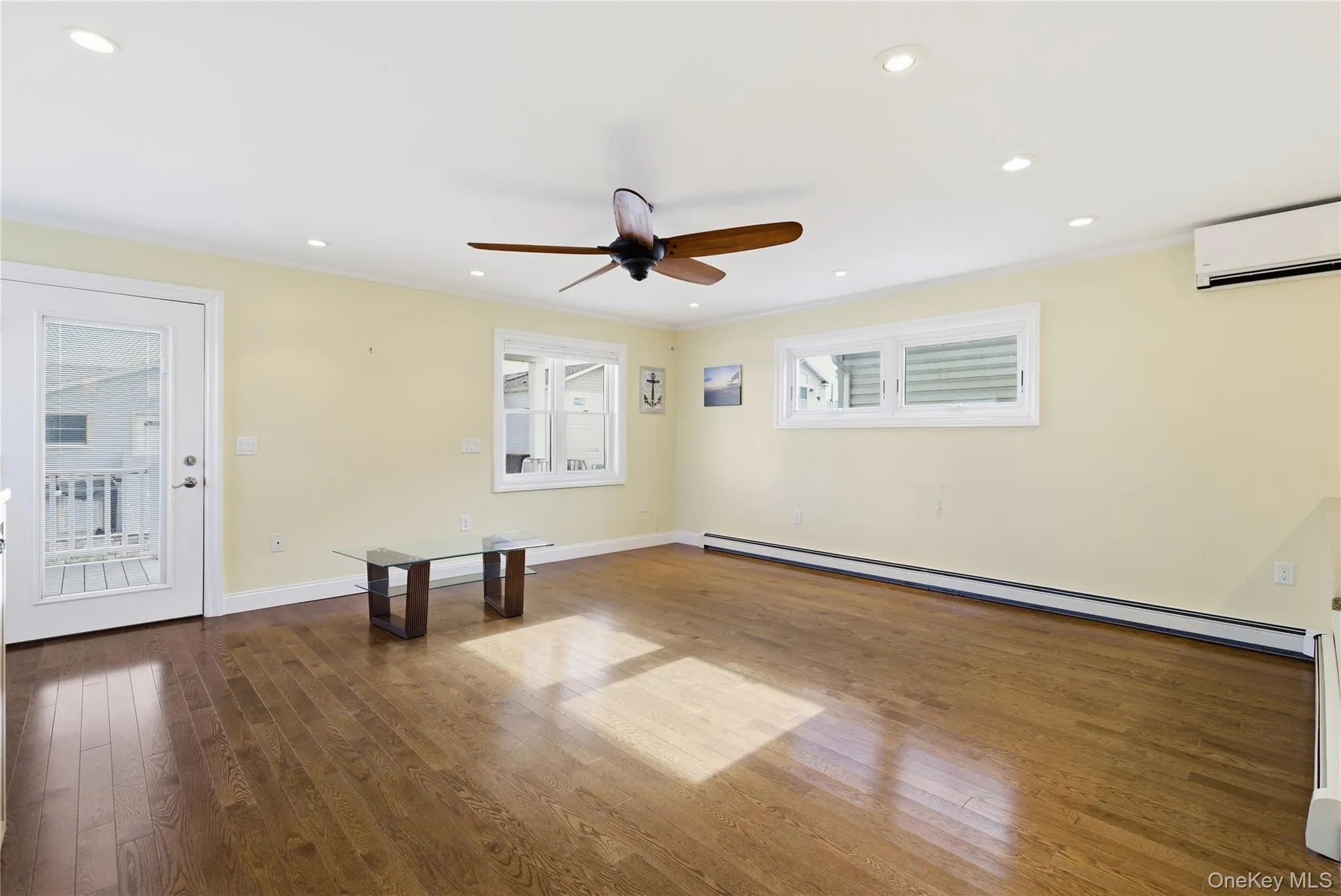 Unfurnished room with dark wood-style flooring, a baseboard heating unit, recessed lighting, ornamental molding, and a wall mounted AC Unfurnished room with dark wood-style flooring, a baseboard heating unit, recessed lighting, ornamental molding, and a wall mounted AC
