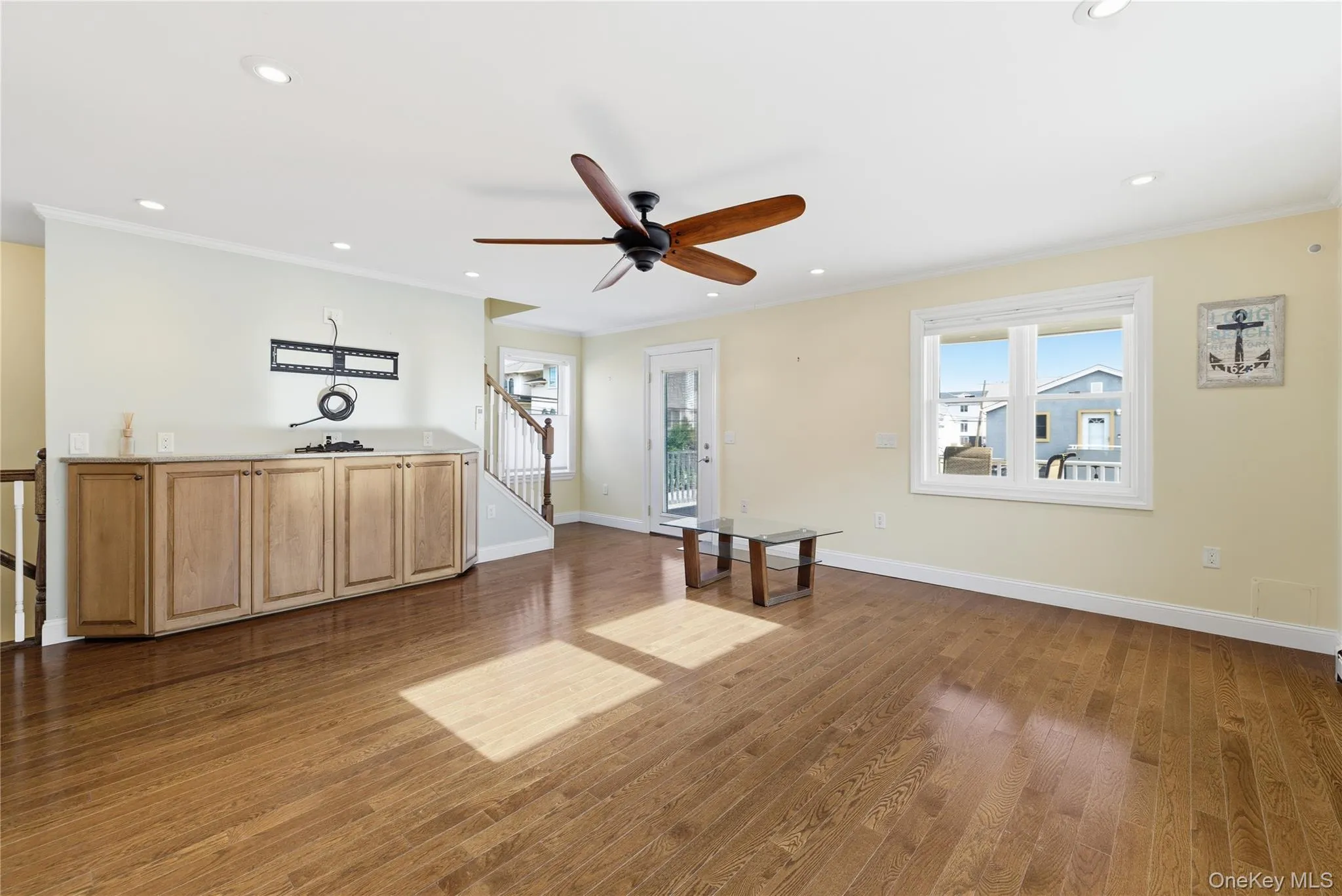 Unfurnished living room with ornamental molding, ceiling fan, recessed lighting, dark wood-type flooring, and stairway Unfurnished living room with ornamental molding, ceiling fan, recessed lighting, dark wood-type flooring, and stairway