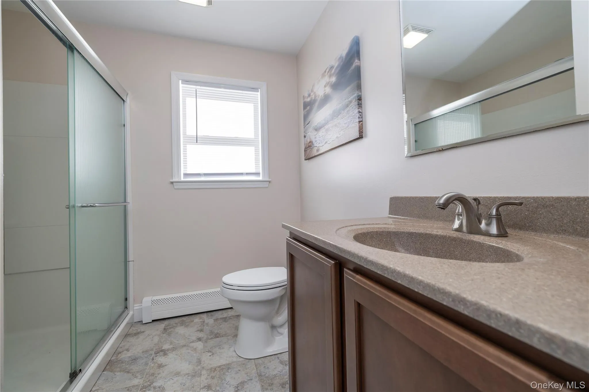 Full bath featuring vanity, a stall shower, and a baseboard heating unit Full bath featuring vanity, a stall shower, and a baseboard heating unit