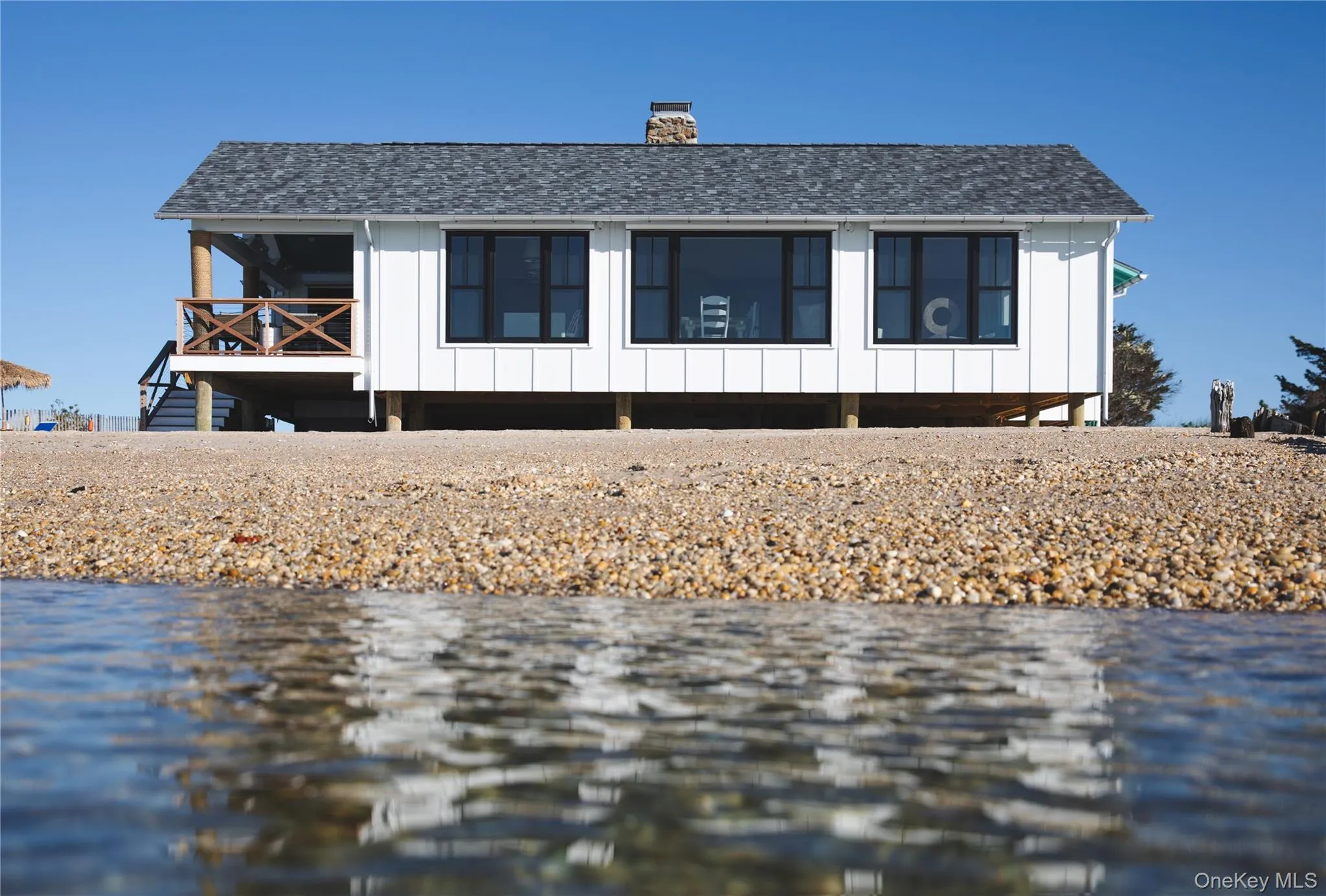 View of front of home featuring a water view, board and batten siding, a chimney, and roof with shingles View of front of home featuring a water view, board and batten siding, a chimney, and roof with shingles