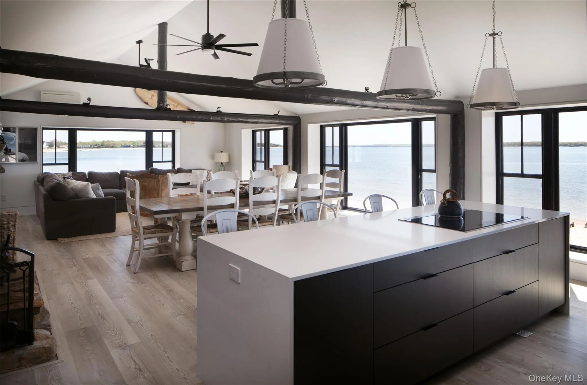 Kitchen featuring modern cabinets, decorative light fixtures, light wood-style flooring, open floor plan, and a water view Kitchen featuring modern cabinets, decorative light fixtures, light wood-style flooring, open floor plan, and a water view