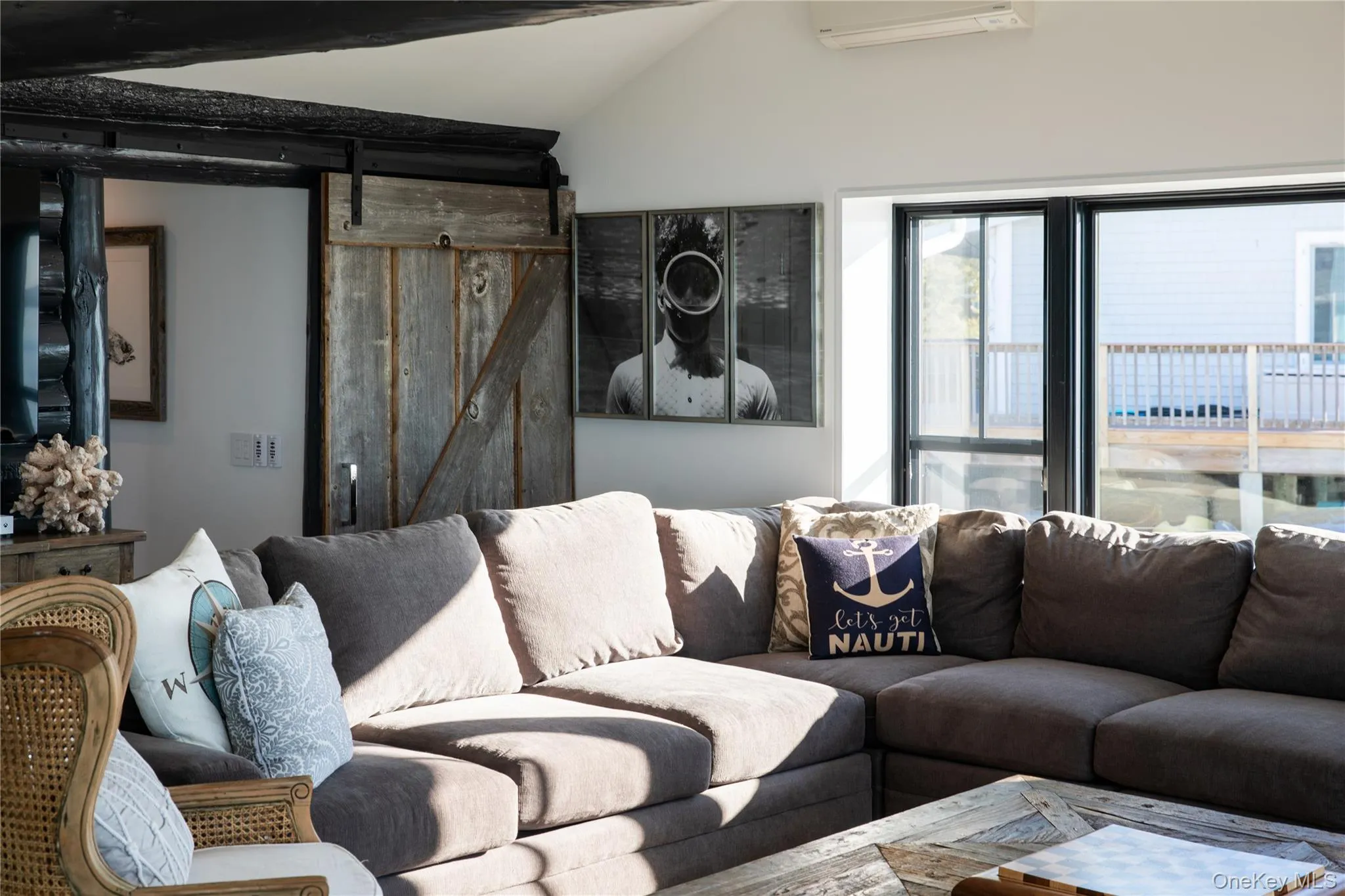 Living room with a barn door, vaulted ceiling, and an AC wall unit Living room with a barn door, vaulted ceiling, and an AC wall unit