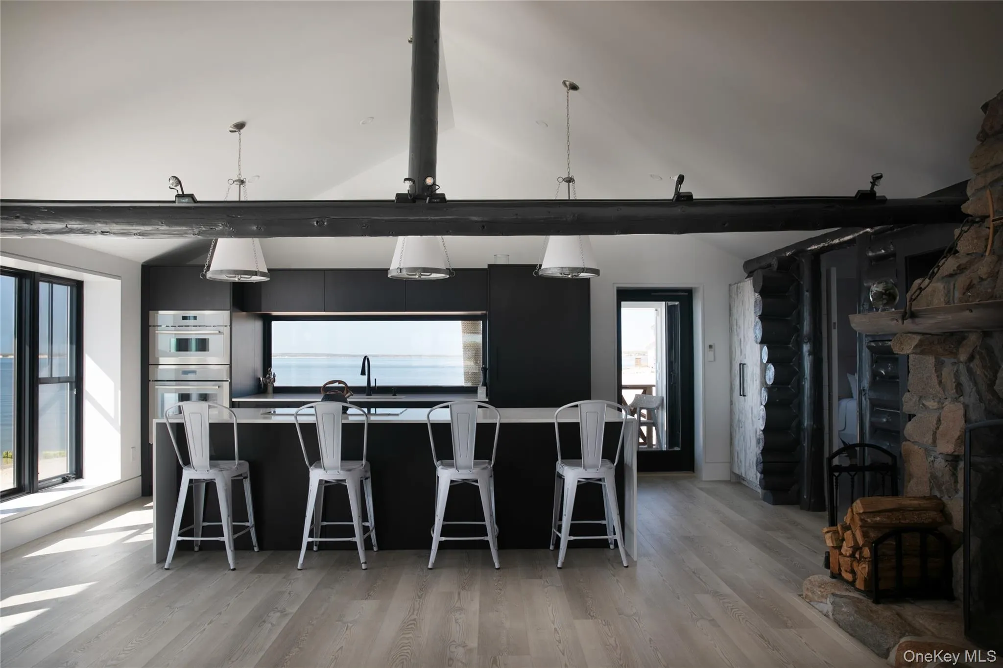 Kitchen featuring a kitchen breakfast bar, dark cabinetry, hanging light fixtures, lofted ceiling, and light wood-type flooring Kitchen featuring a kitchen breakfast bar, dark cabinetry, hanging light fixtures, lofted ceiling, and light wood-type flooring