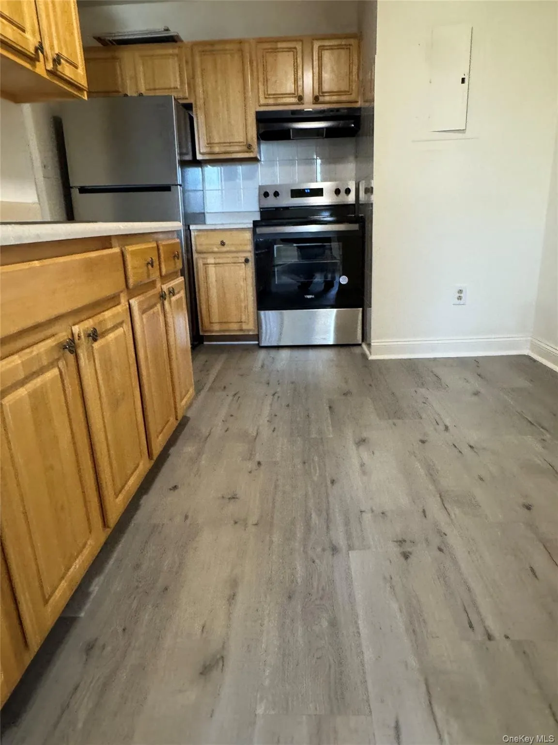 Kitchen featuring light countertops, appliances with stainless steel finishes, tasteful backsplash, and dark wood-style floors Kitchen featuring light countertops, appliances with stainless steel finishes, tasteful backsplash, and dark wood-style floors