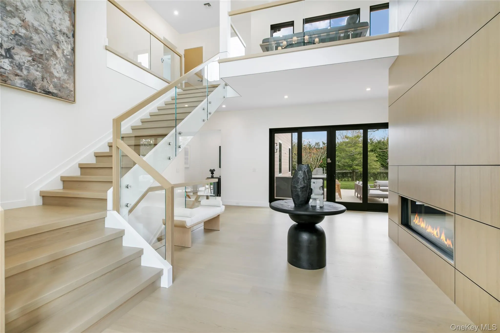 Stairs featuring a high ceiling, a glass covered fireplace, recessed lighting, and wood finished floors Stairs featuring a high ceiling, a glass covered fireplace, recessed lighting, and wood finished floors