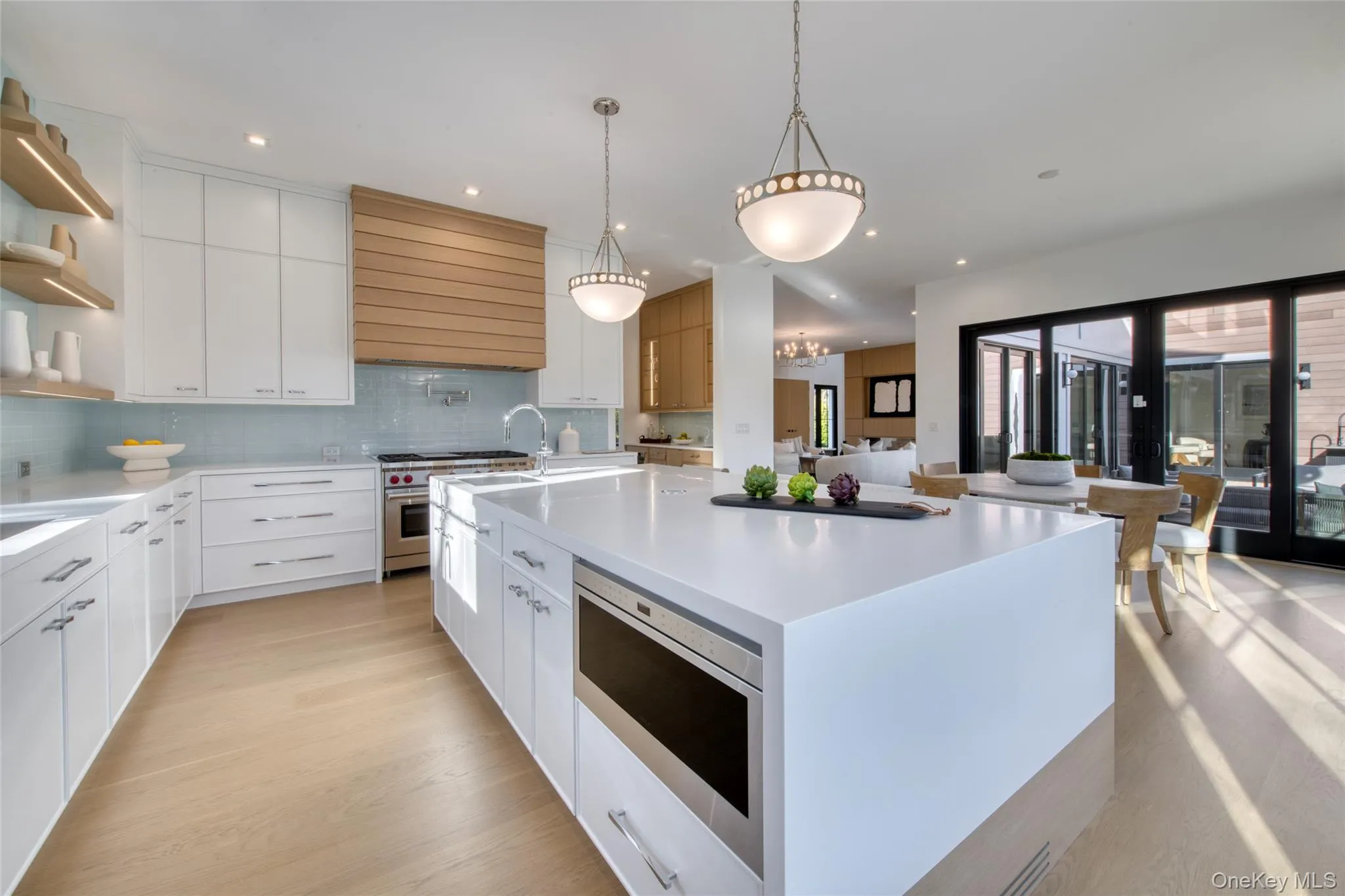 Kitchen featuring open shelves, appliances with stainless steel finishes, a large island, light wood-style floors, and white cabinets Kitchen featuring open shelves, appliances with stainless steel finishes, a large island, light wood-style floors, and white cabinets