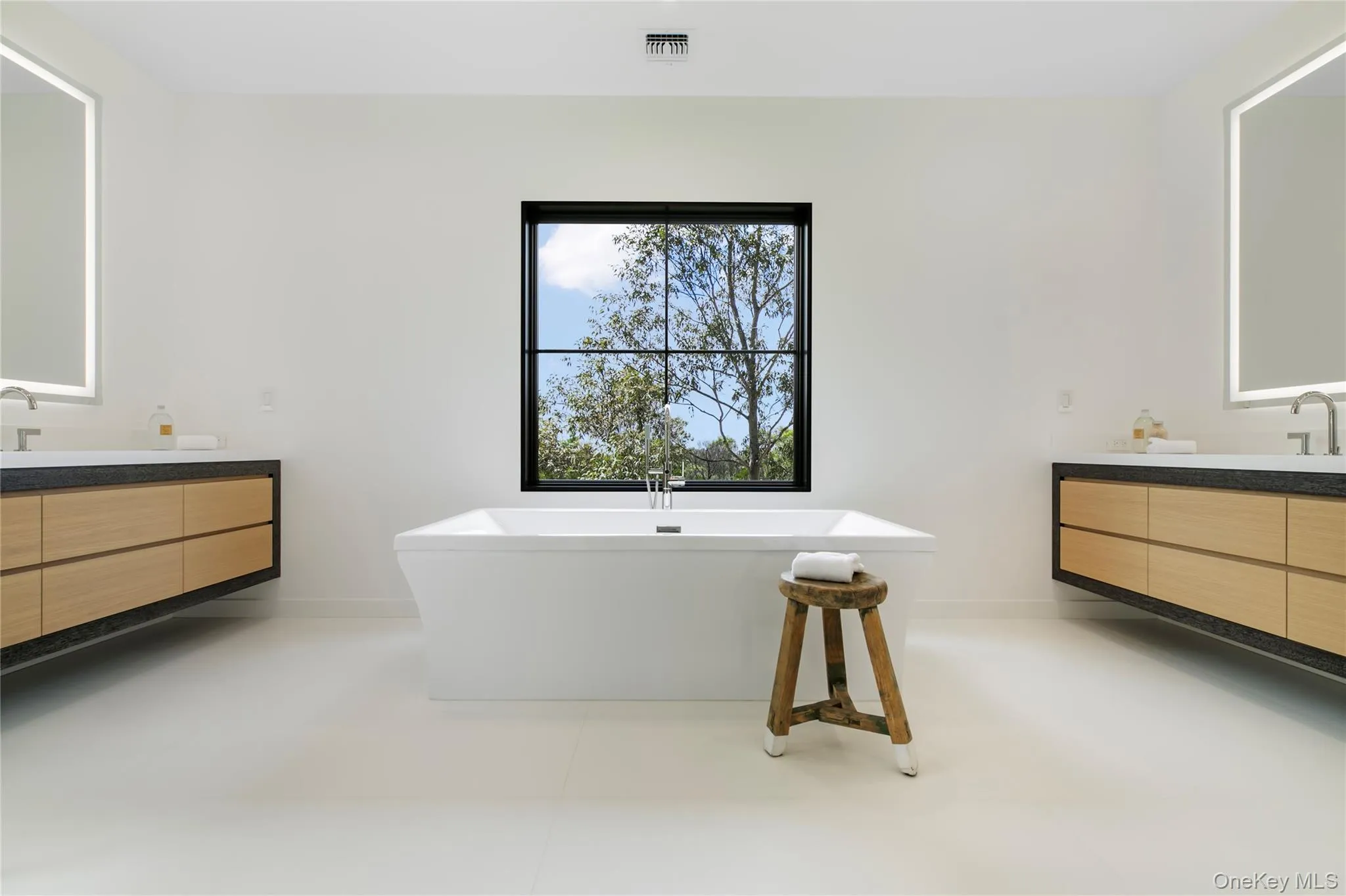 Bathroom featuring two vanities, a freestanding bath, and light tile patterned floors Bathroom featuring two vanities, a freestanding bath, and light tile patterned floors