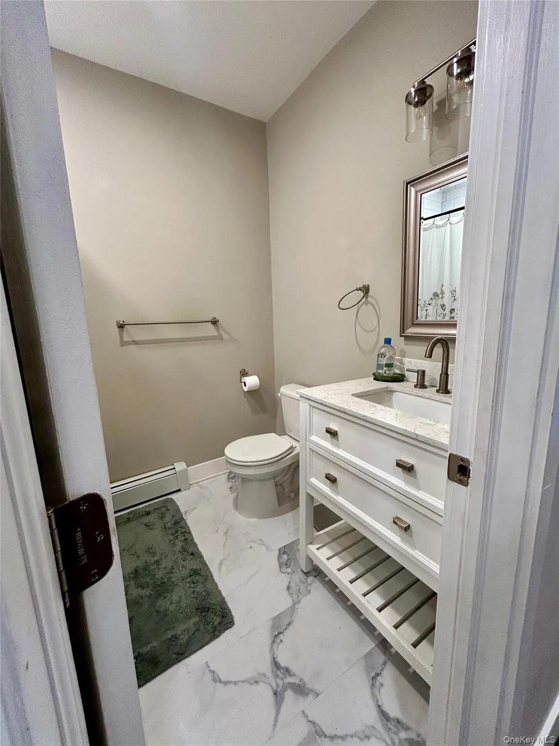 Bathroom with vanity, baseboard heating, and light marble finish floors Bathroom with vanity, baseboard heating, and light marble finish floors