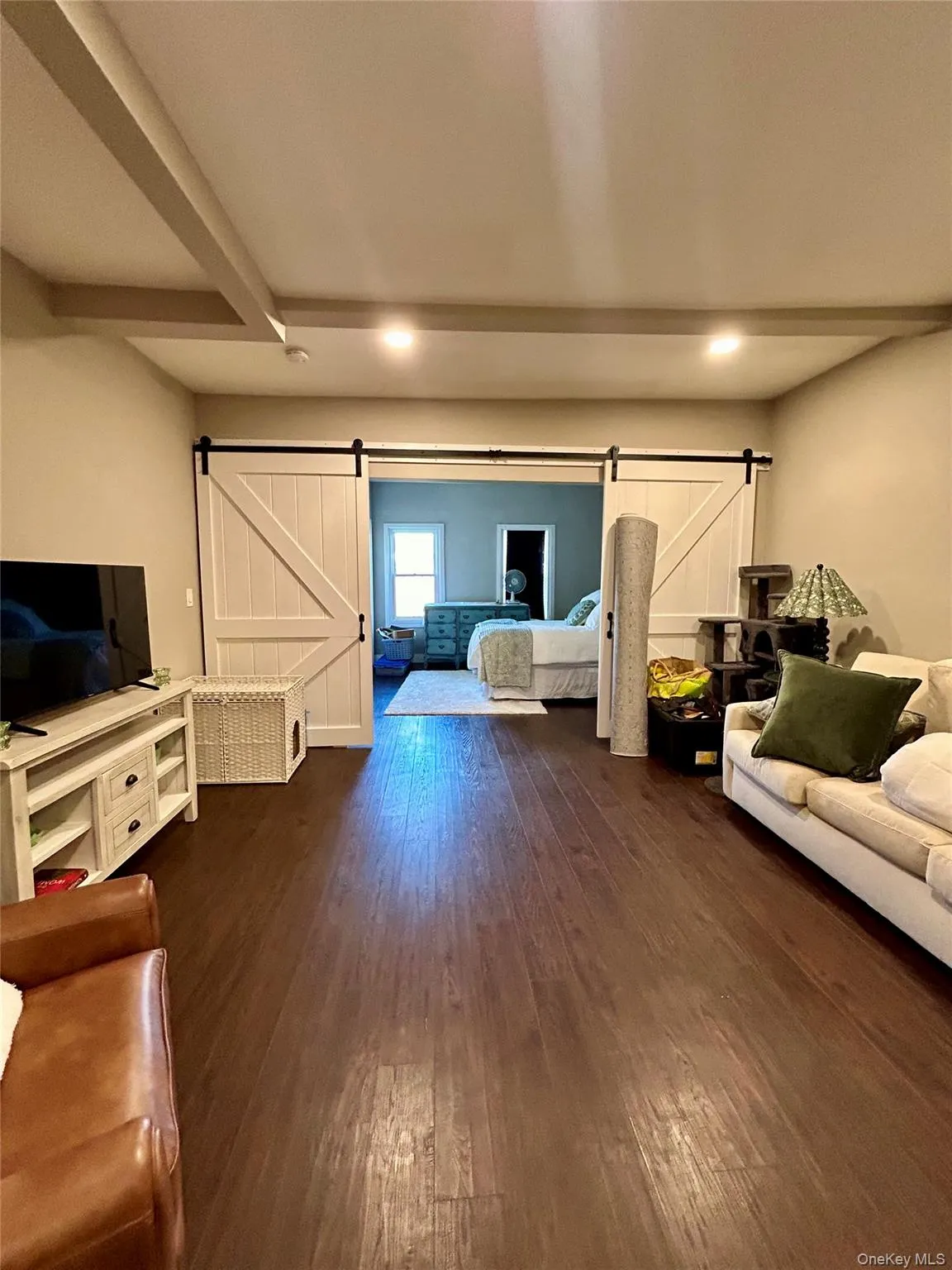 Living area featuring a barn door, dark wood-style floors, and beamed ceiling Living area featuring a barn door, dark wood-style floors, and beamed ceiling