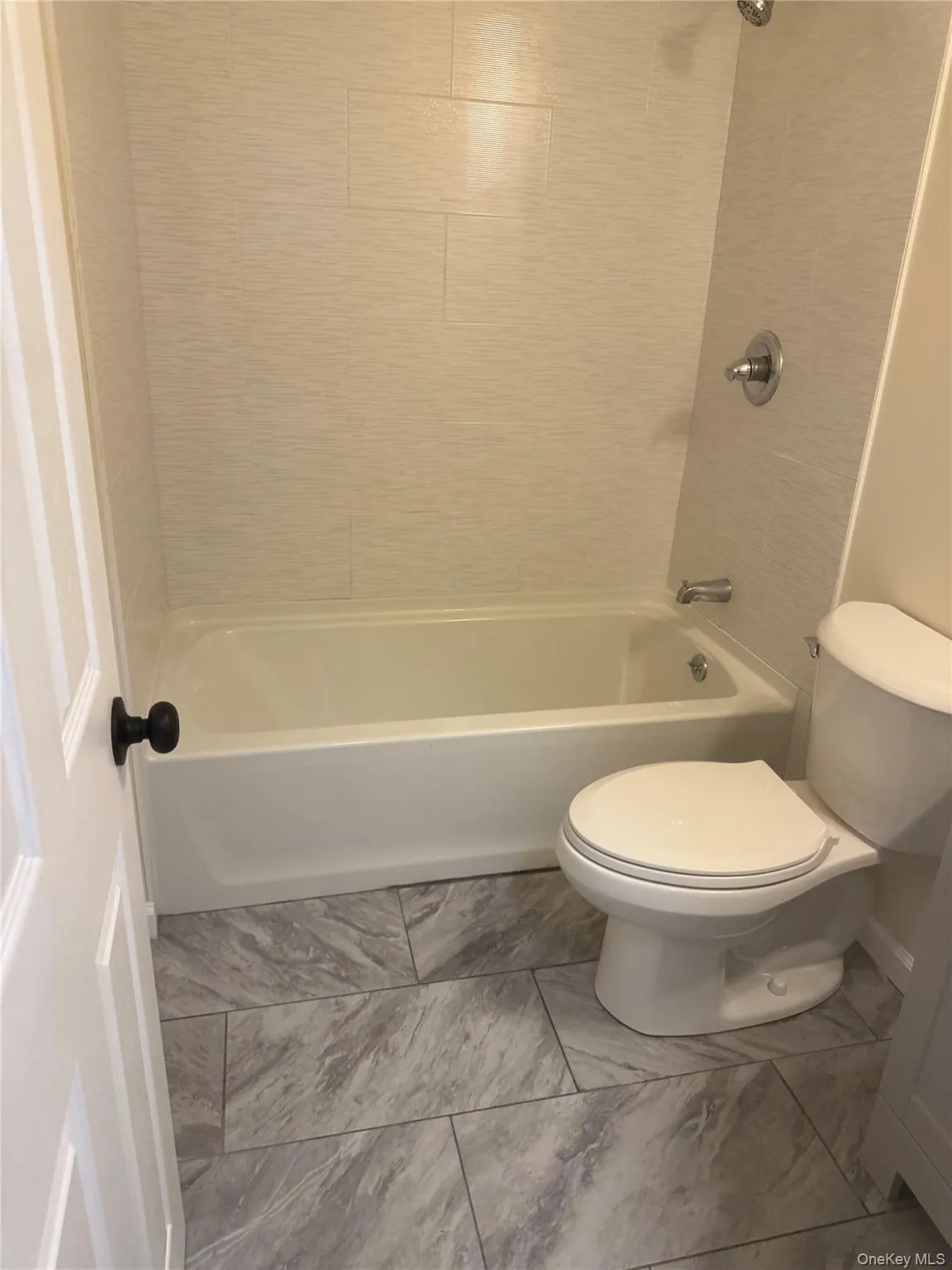 Full bath featuring shower / bathtub combination and light marble finish floors Full bath featuring shower / bathtub combination and light marble finish floors