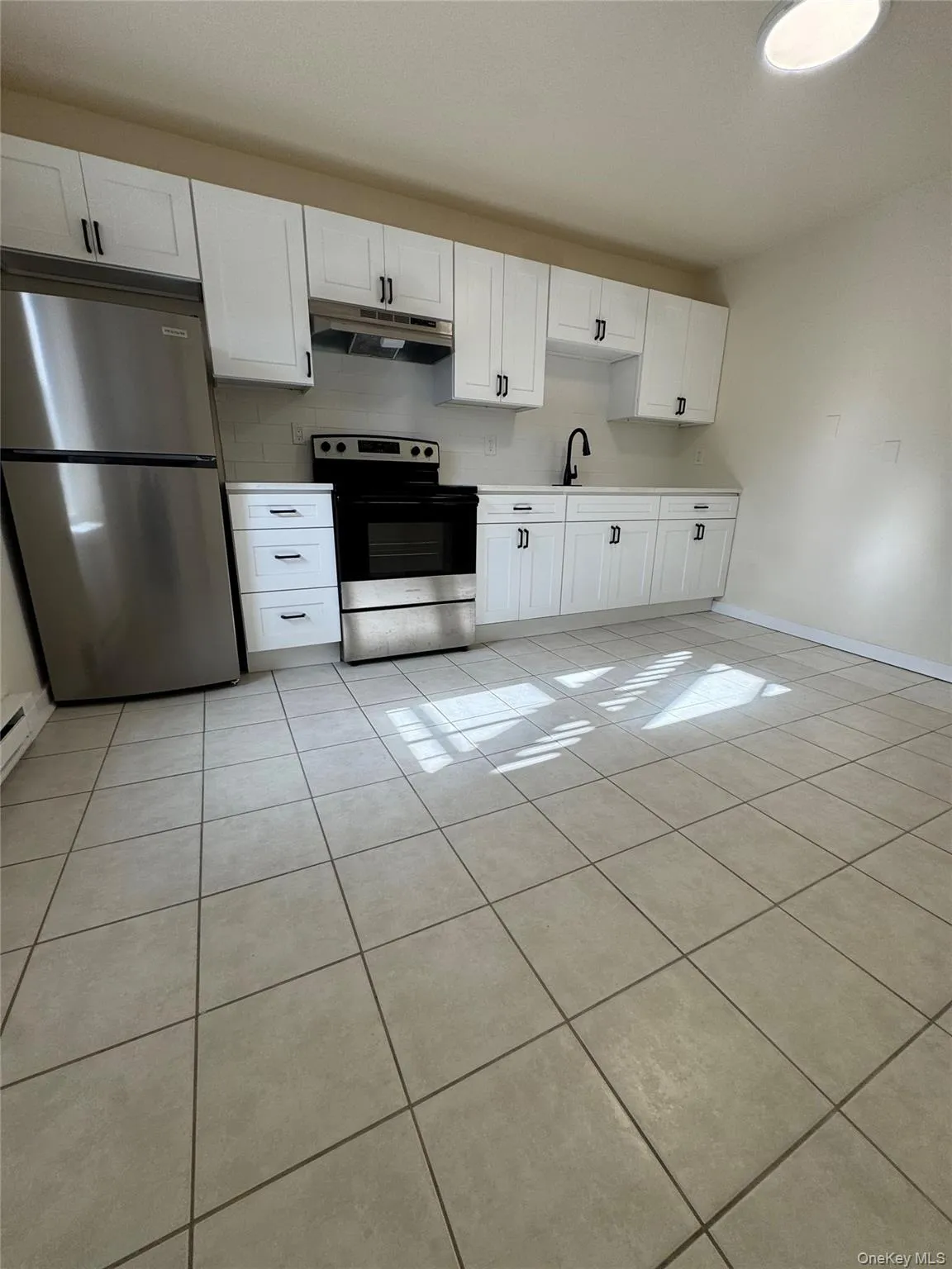 Kitchen with white cabinetry, appliances with stainless steel finishes, light tile patterned flooring, and light countertops Kitchen with white cabinetry, appliances with stainless steel finishes, light tile patterned flooring, and light countertops