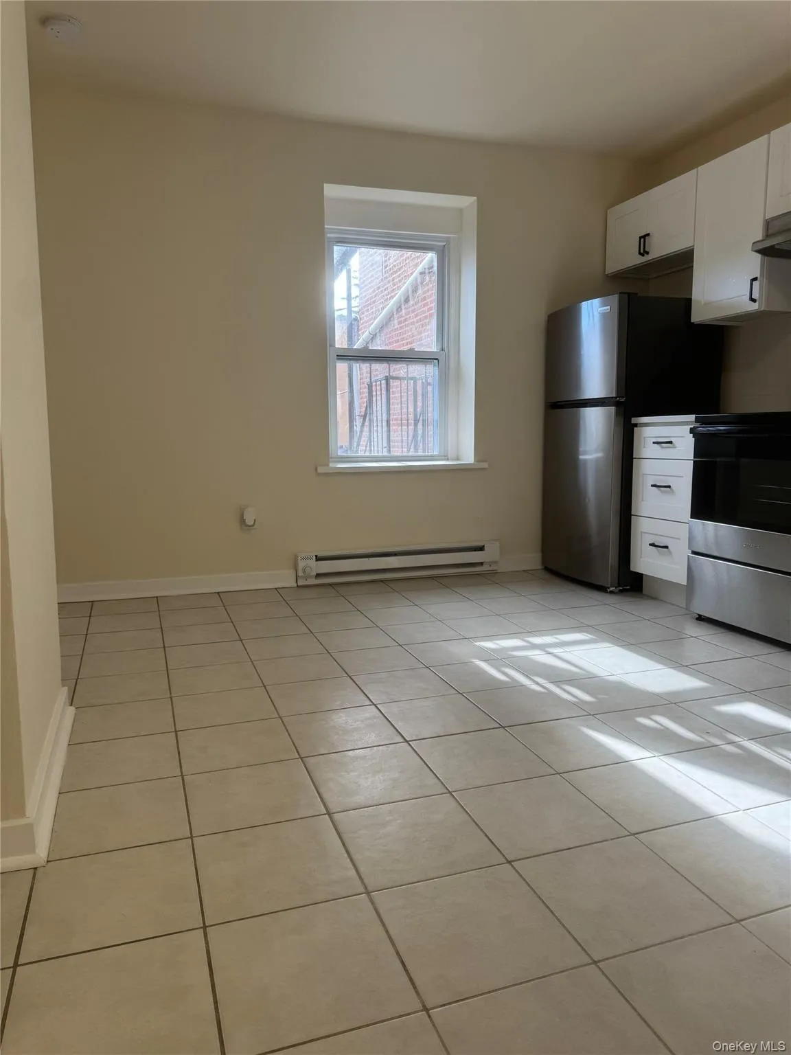 Kitchen with light tile patterned flooring, white cabinetry, stainless steel appliances, and baseboard heating Kitchen with light tile patterned flooring, white cabinetry, stainless steel appliances, and baseboard heating